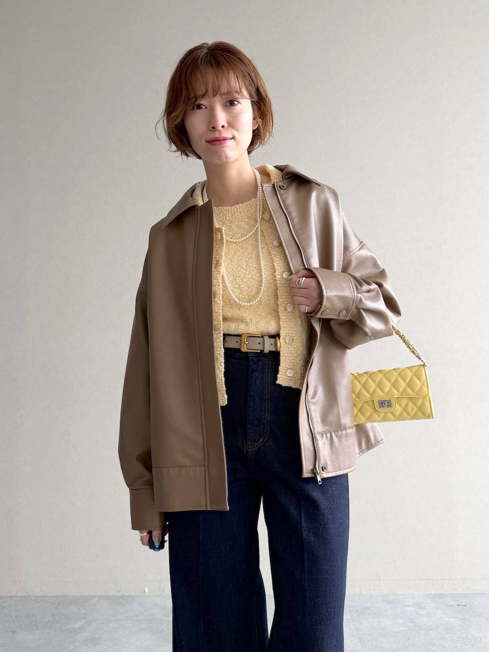 ホワイト系のサンダル、ブラウン系のブルゾン、イエロー系のカーディガン/ボレロを着用したレディースの春コーディネートの4枚目の写真