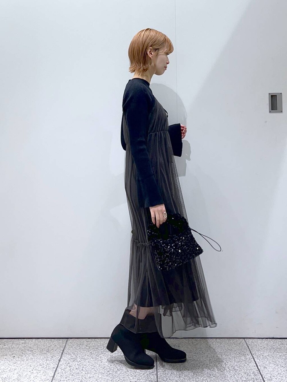 ブラック系のブーツ、ブラック系のハンドバッグ、グレー系のワンピースを着用したレディースの冬コーディネートの2枚目の写真