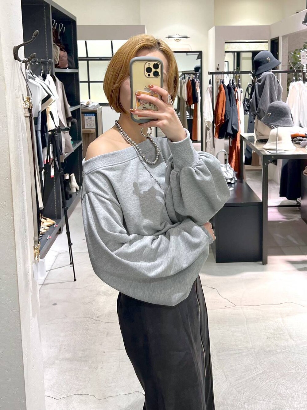 シルバー系のショルダーバッグ、ブラック系のブーツ、グレー系のスカートを着用したレディースの秋コーディネートの4枚目の写真