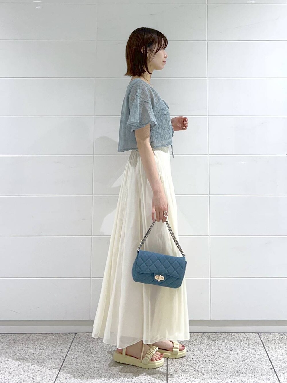 ホワイト系のサンダル、ブルー系のショルダーバッグ、ホワイト系のスカートを着用したレディースの春コーディネートの3枚目の写真