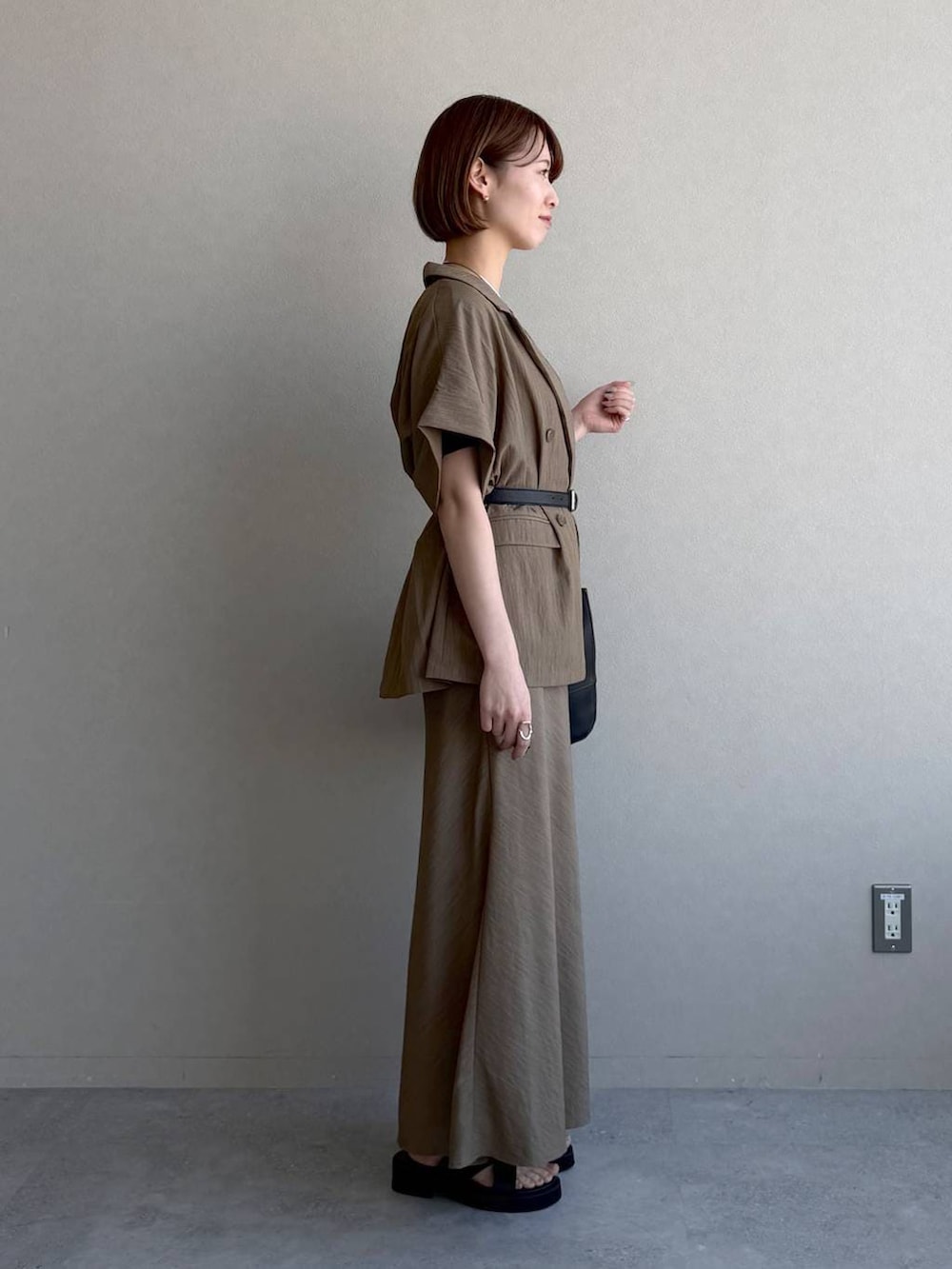 ブラック系のサンダル、ブラック系のTシャツ/カットソー、ブラウン系のスカートを着用したレディースの春コーディネートの2枚目の写真