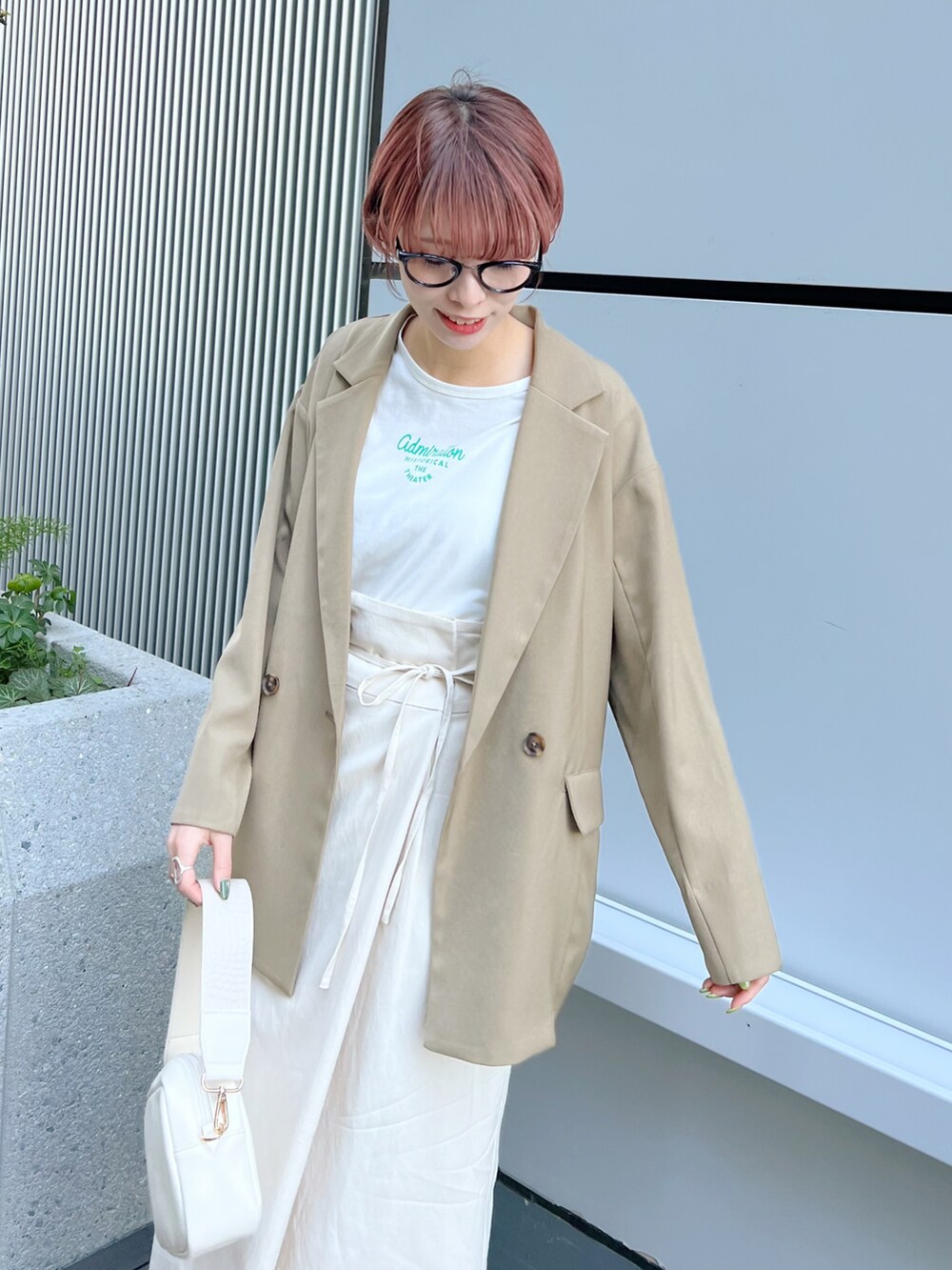 ベージュ系のテーラードジャケット、ホワイト系のスカート、ホワイト系のサンダルを着用したレディースの春コーディネートの3枚目の写真