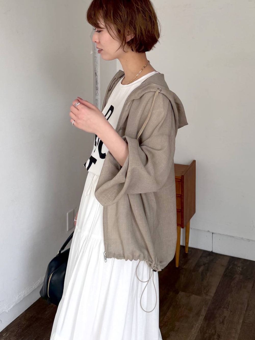 ブラック系のハンドバッグ、ブラック系のサンダル、ホワイト系のスカートを着用したレディースの春コーディネートの6枚目の写真