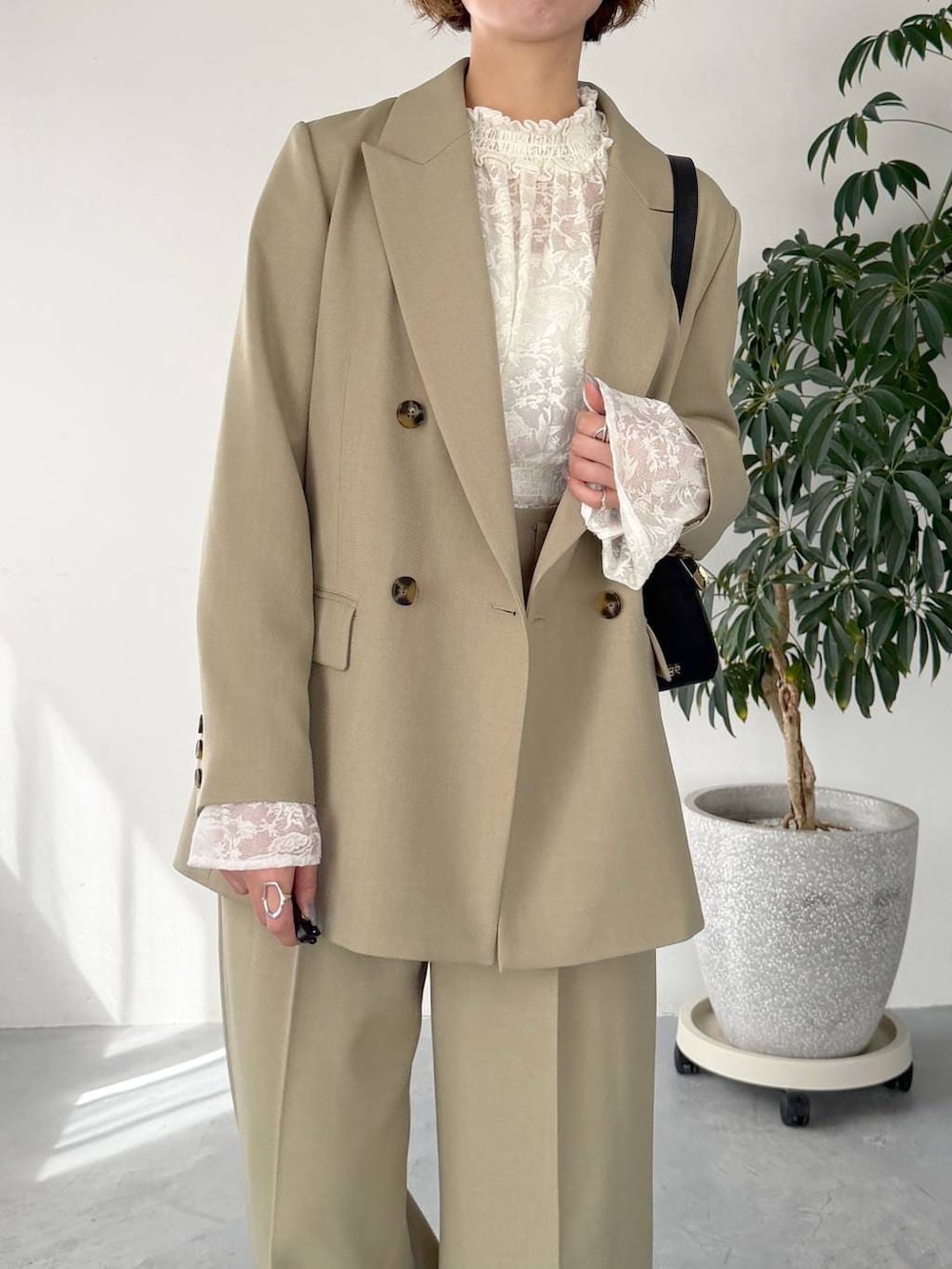 ベージュ系のテーラードジャケット、ベージュ系のその他パンツ、ブラック系のサンダルを着用したレディースの春コーディネートの4枚目の写真