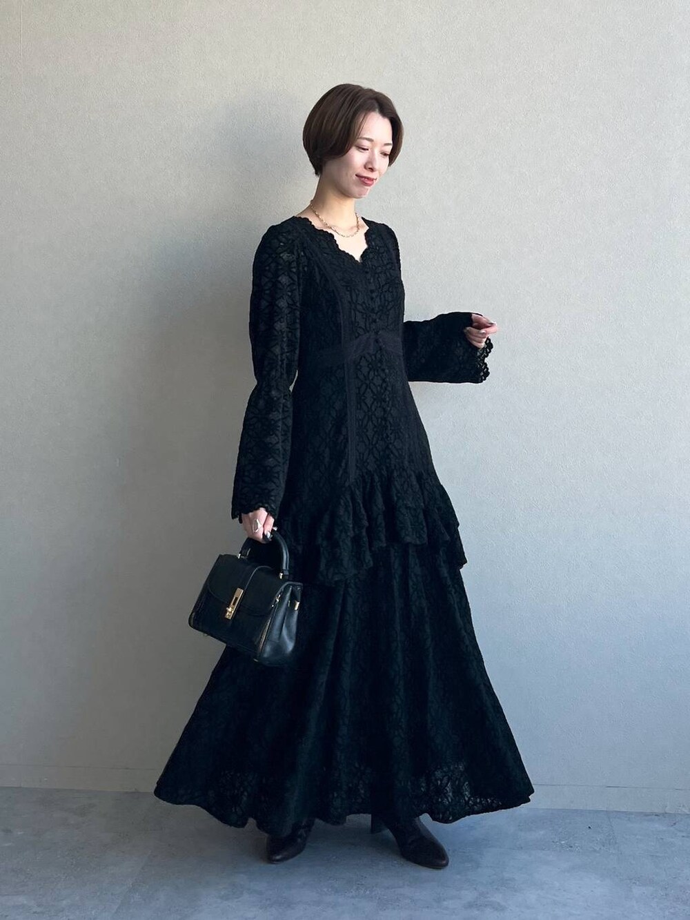 ブラック系のワンピース、パープル系のチェスターコート、ブラック系のブーツを着用したレディースの冬コーディネートの8枚目の写真