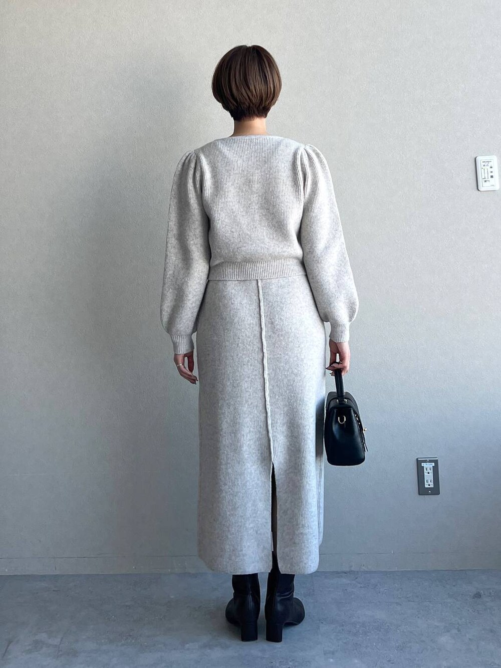 ブラック系のブーツ、ブラック系のショルダーバッグ、ホワイト系のワンピースを着用したレディースの冬コーディネートの3枚目の写真