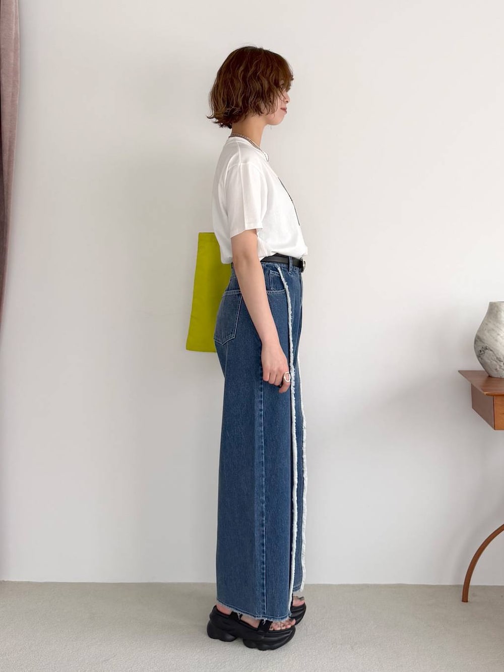 ブルー系のデニムパンツ、ブラック系のサンダル、ブラック系のベルトを着用したレディースの春コーディネートの2枚目の写真