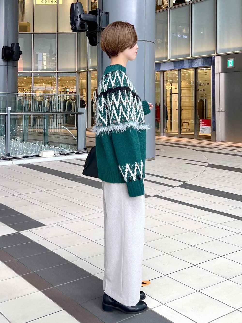 ブラック系のトートバッグ、ブラック系のブーツ、グリーン系のニット/セーターを着用したレディースの秋コーディネートの2枚目の写真