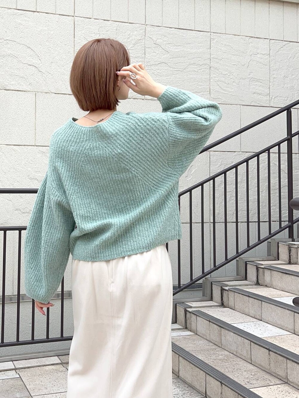 グレー系のノーカラーコート、ブラック系のショルダーバッグ、ブラック系のブーツを着用したレディースの秋コーディネートの8枚目の写真