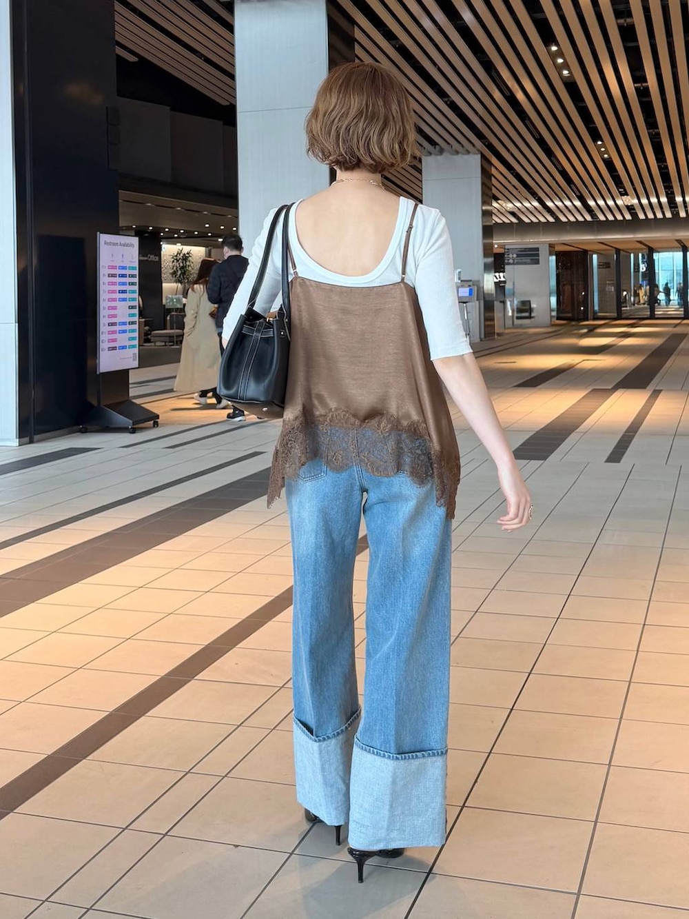 ブラック系のサンダル、ブラウン系のキャミソール、ホワイト系のノーカラージャケットを着用したレディースの春コーディネートの6枚目の写真