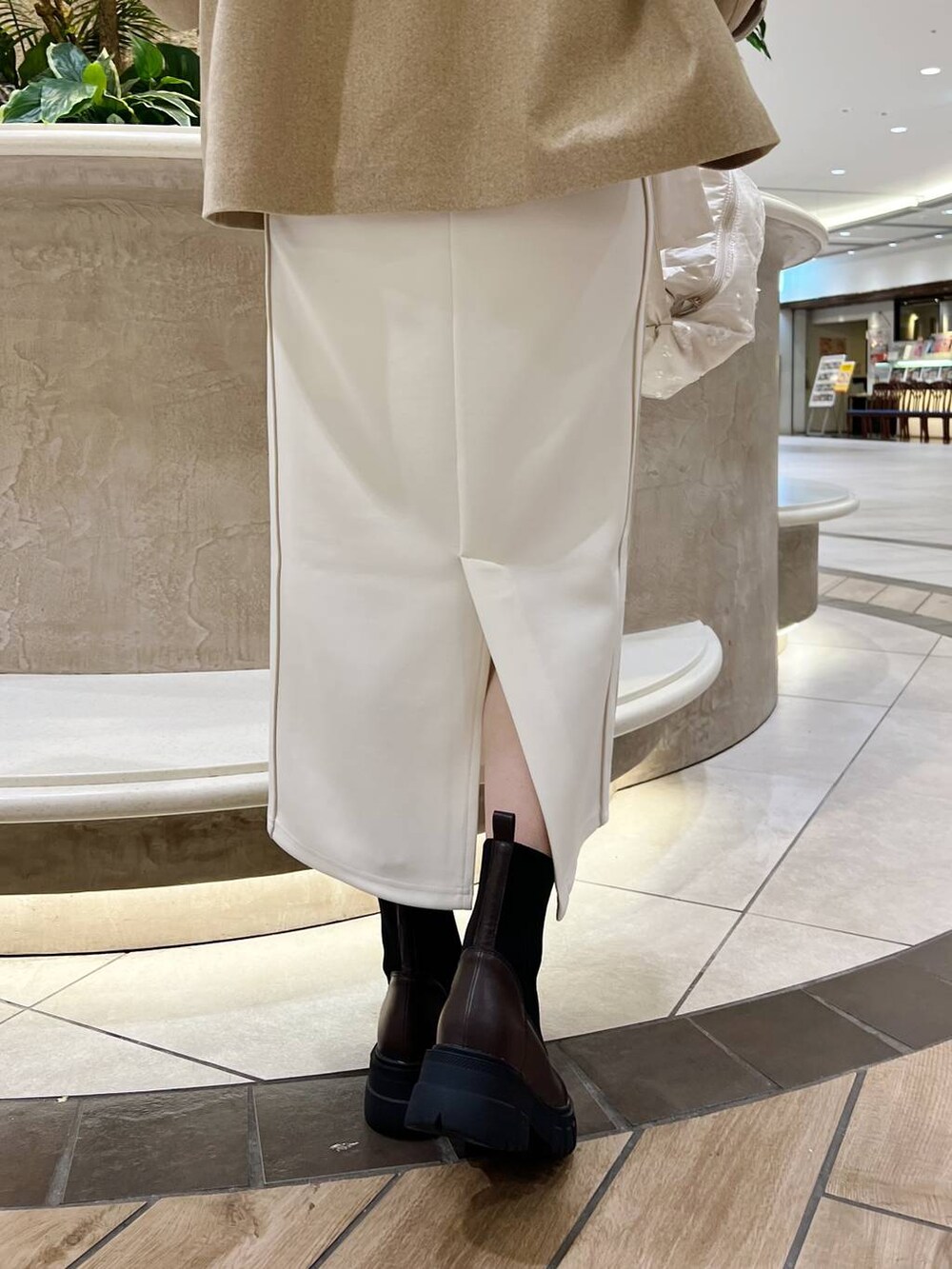 ベージュ系のピーコート、ホワイト系のショルダーバッグ、ブラウン系のブーツを着用したレディースの秋コーディネートの8枚目の写真