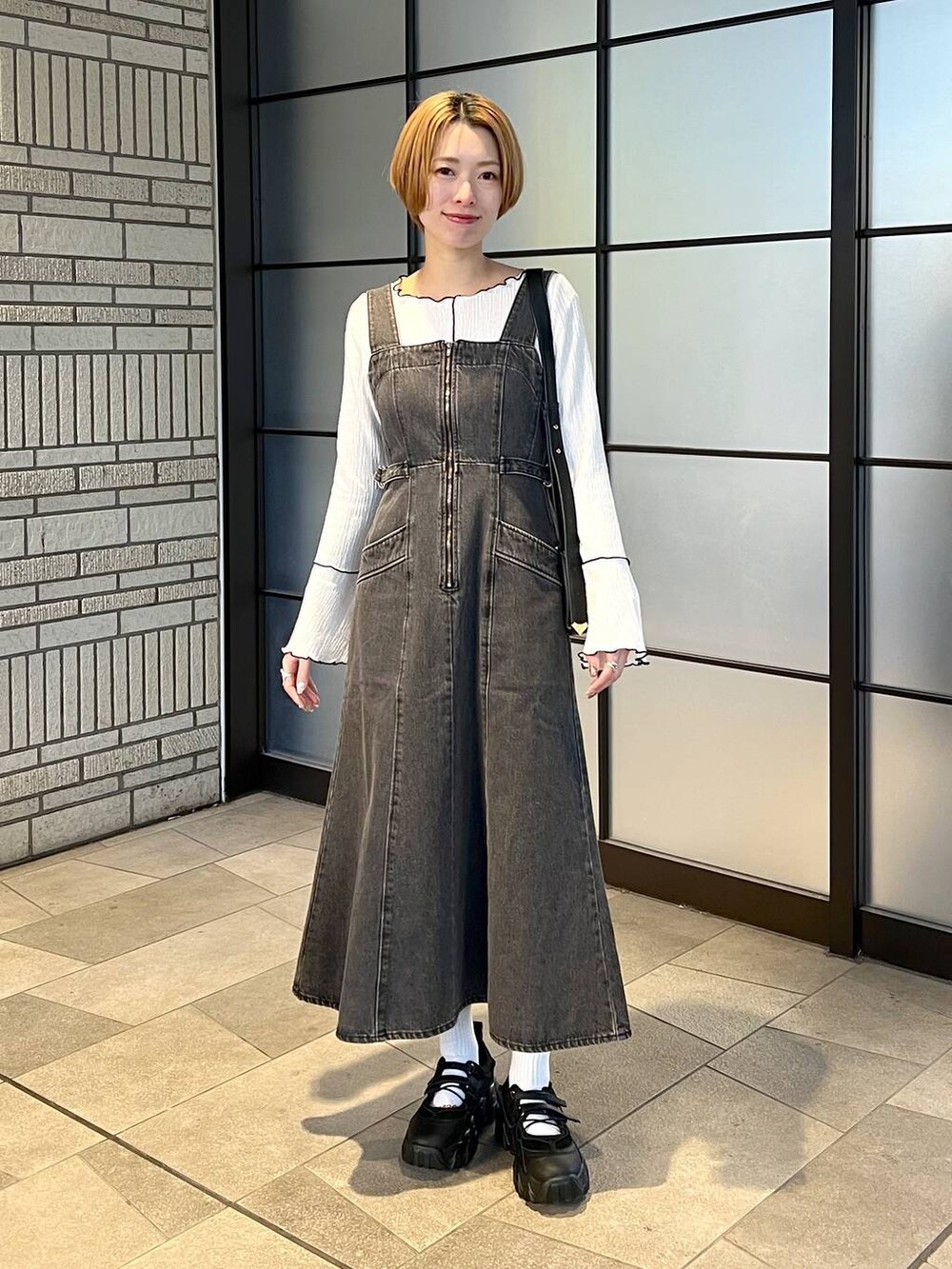 ブラック系のデニムジャケット、ブラック系のジャンパースカート、ブラック系のバレエシューズを着用したレディースの冬コーディネートの4枚目の写真