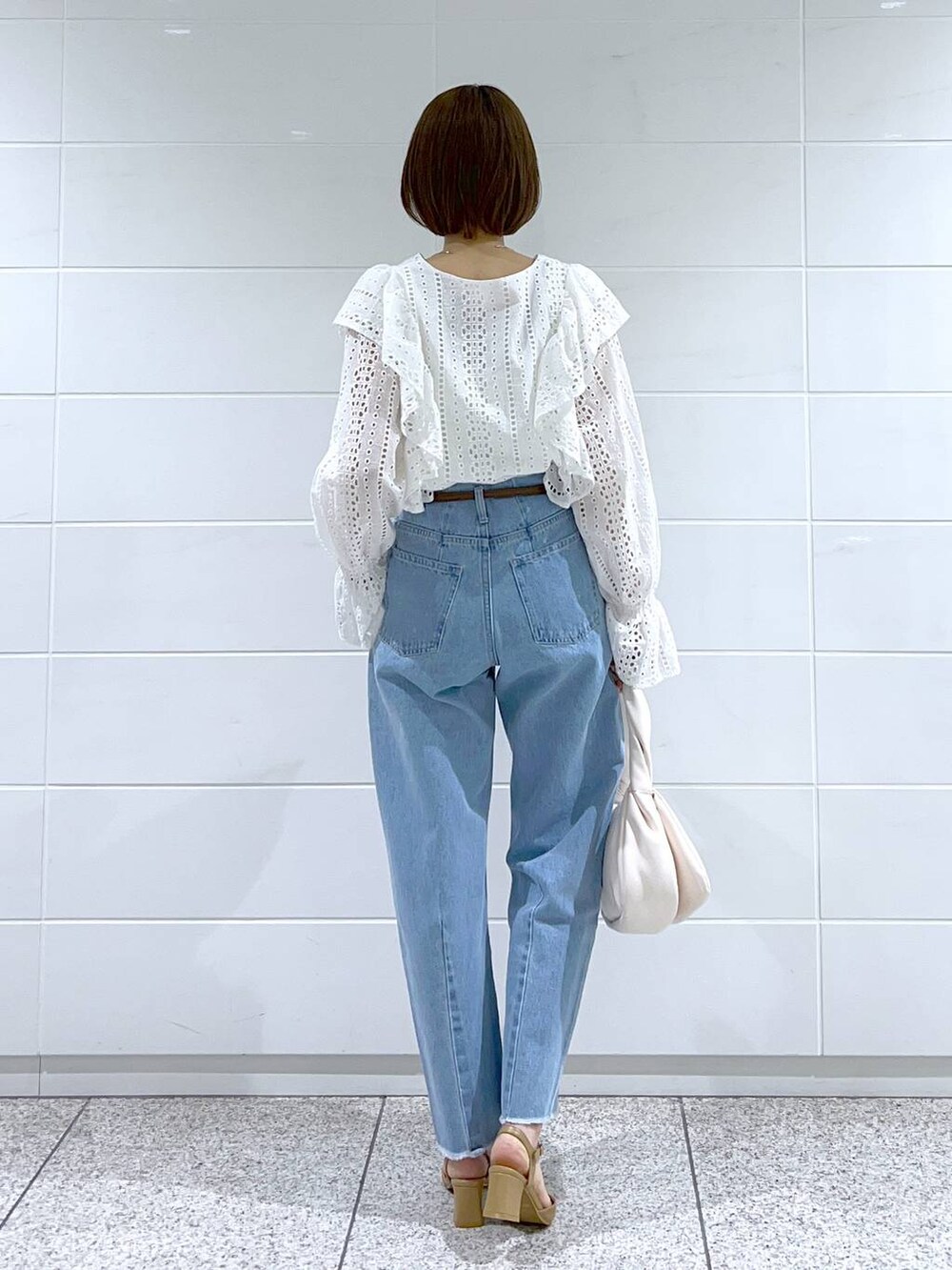 ホワイト系のシャツ/ブラウス、ホワイト系のハンドバッグ、ベージュ系のパンプスを着用したレディースの冬コーディネートの3枚目の写真