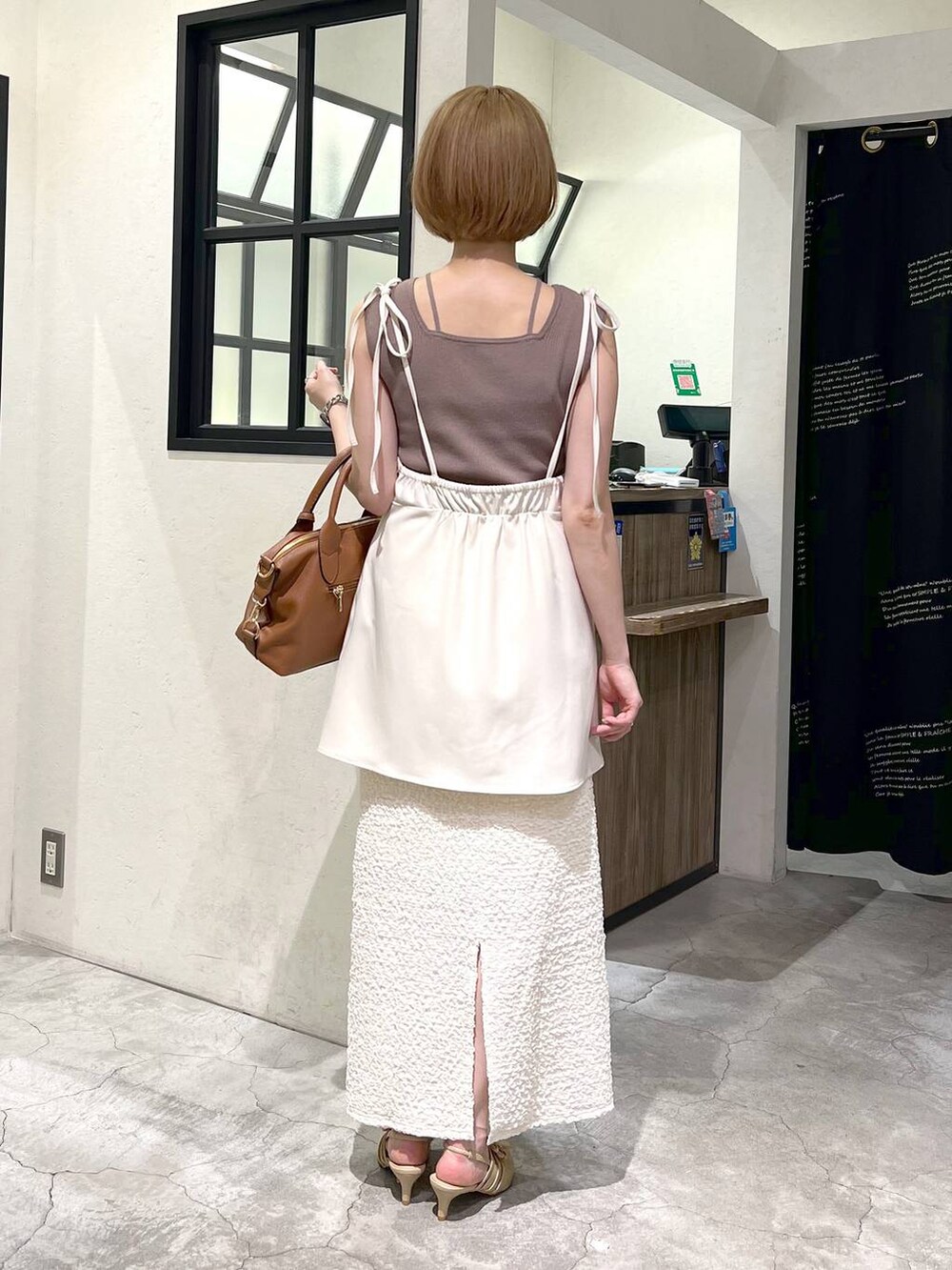 ブラウン系のタンクトップ、ホワイト系のスカート、ゴールド系のパンプスを着用したレディースの夏コーディネートの3枚目の写真
