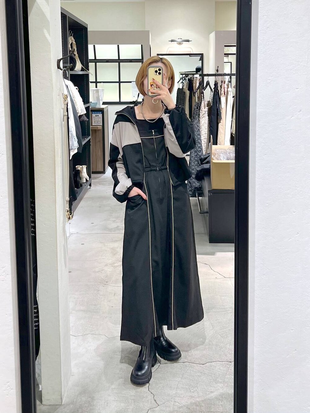 シルバー系のショルダーバッグ、ブラック系のブーツ、ブラック系のワンピースを着用したレディースの秋コーディネートの4枚目の写真