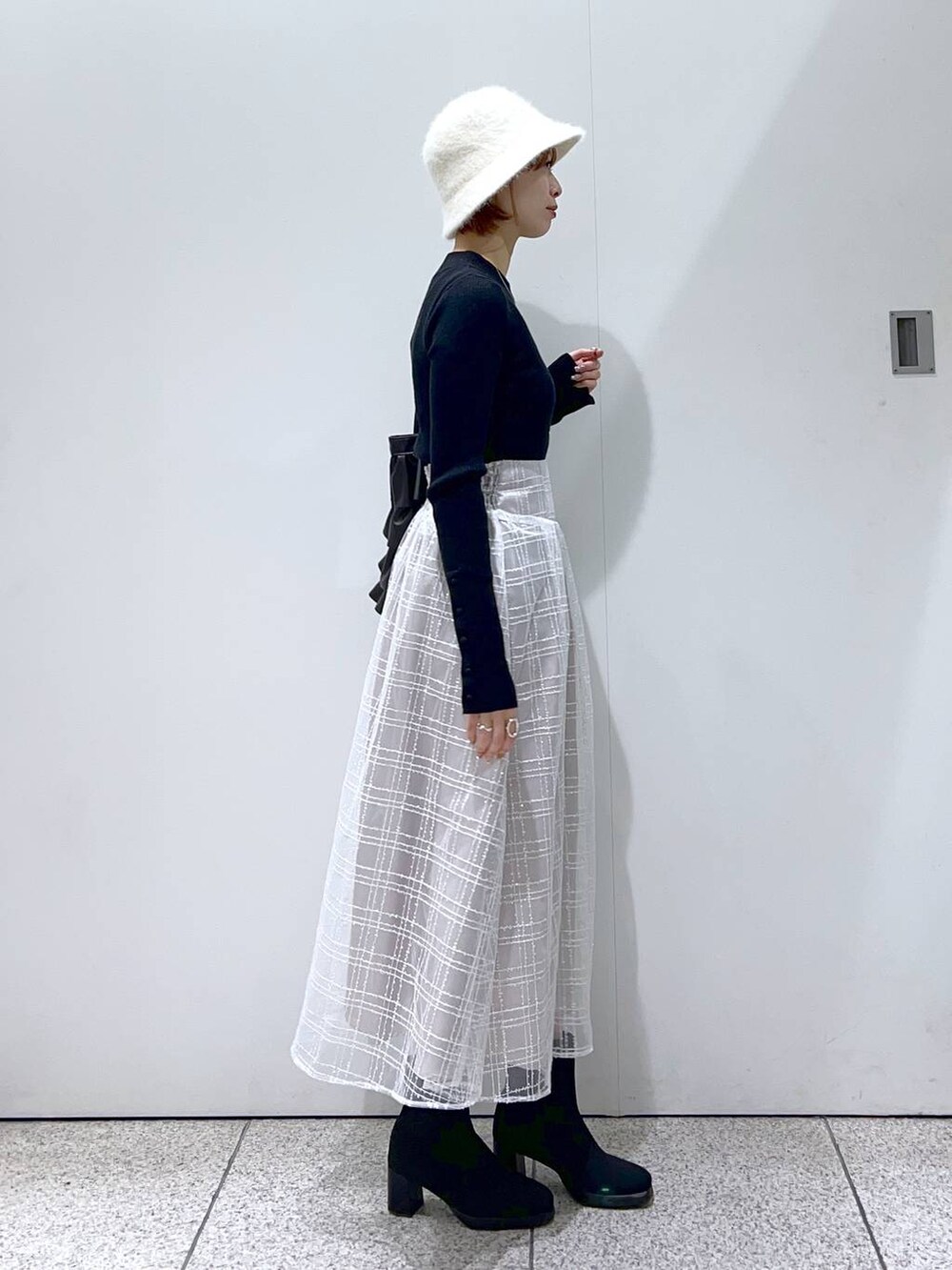 ブラック系のブーツ、ブラック系のニット/セーター、グレー系のスカートを着用したレディースの冬コーディネートの2枚目の写真