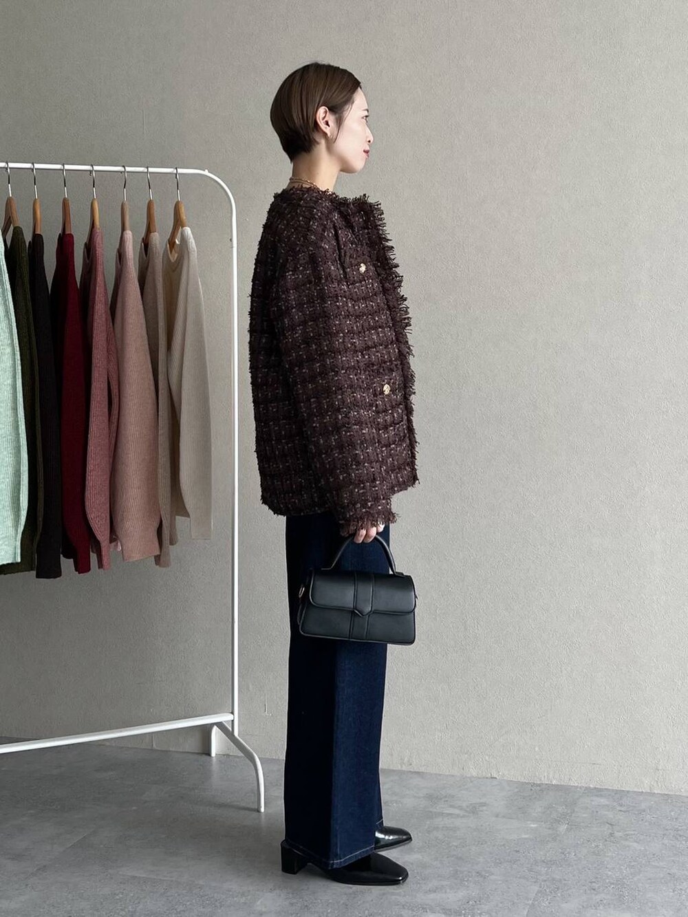 ブラウン系のノーカラージャケット、ブルー系のデニムパンツ、オレンジ系のニット/セーターを着用したレディースの秋コーディネートの2枚目の写真