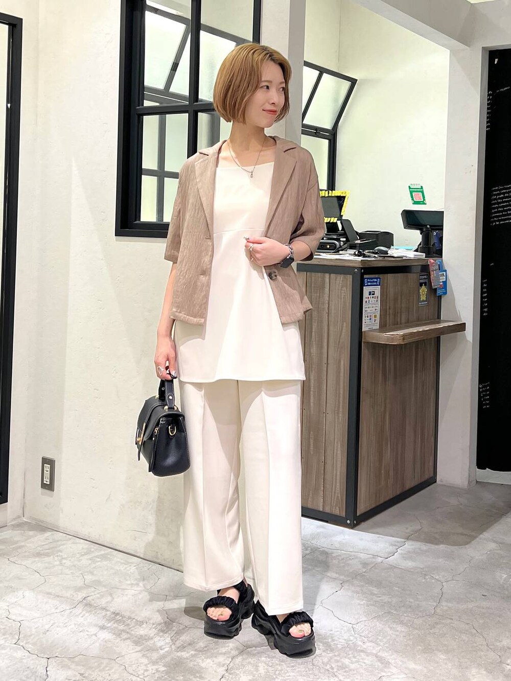 ブラック系のサンダル、ベージュ系のテーラードジャケット、ブラック系のショルダーバッグを着用したレディースの夏コーディネートの2枚目の写真