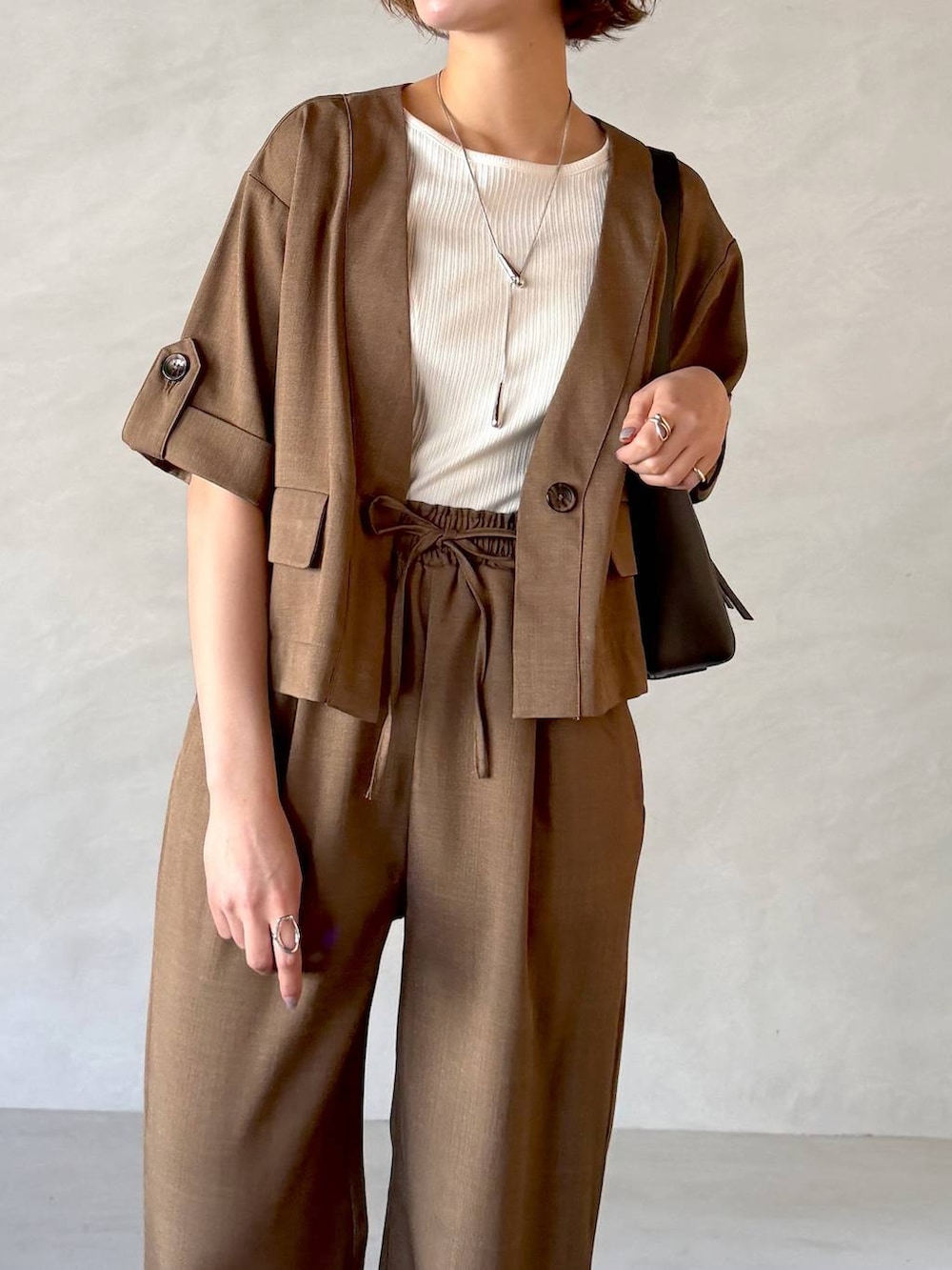 ブラック系のサンダル、ブラック系のショルダーバッグ、ブラウン系のセットアップを着用したレディースの春コーディネートの4枚目の写真