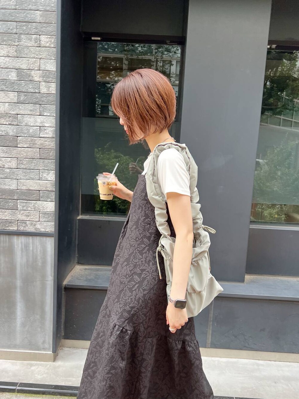 グリーン系のショルダーバッグ、ホワイト系のTシャツ/カットソー、ブラック系のサンダルを着用したレディースの夏コーディネートの2枚目の写真