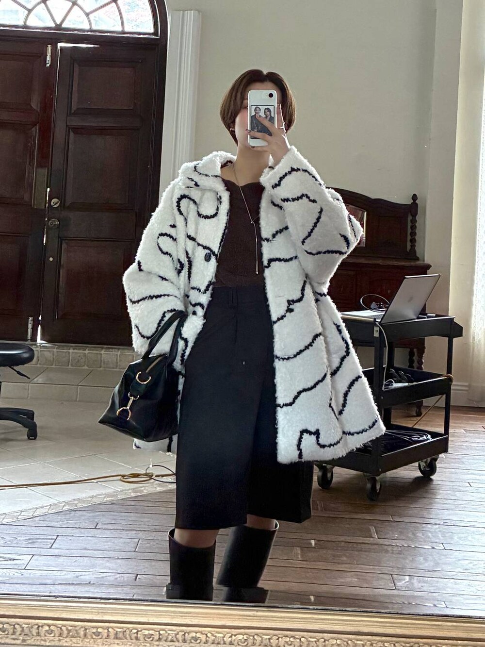 ブラウン系のニット/セーター、ブラック系のボストンバッグ、ブラック系のブーツを着用したレディースの冬コーディネートの7枚目の写真