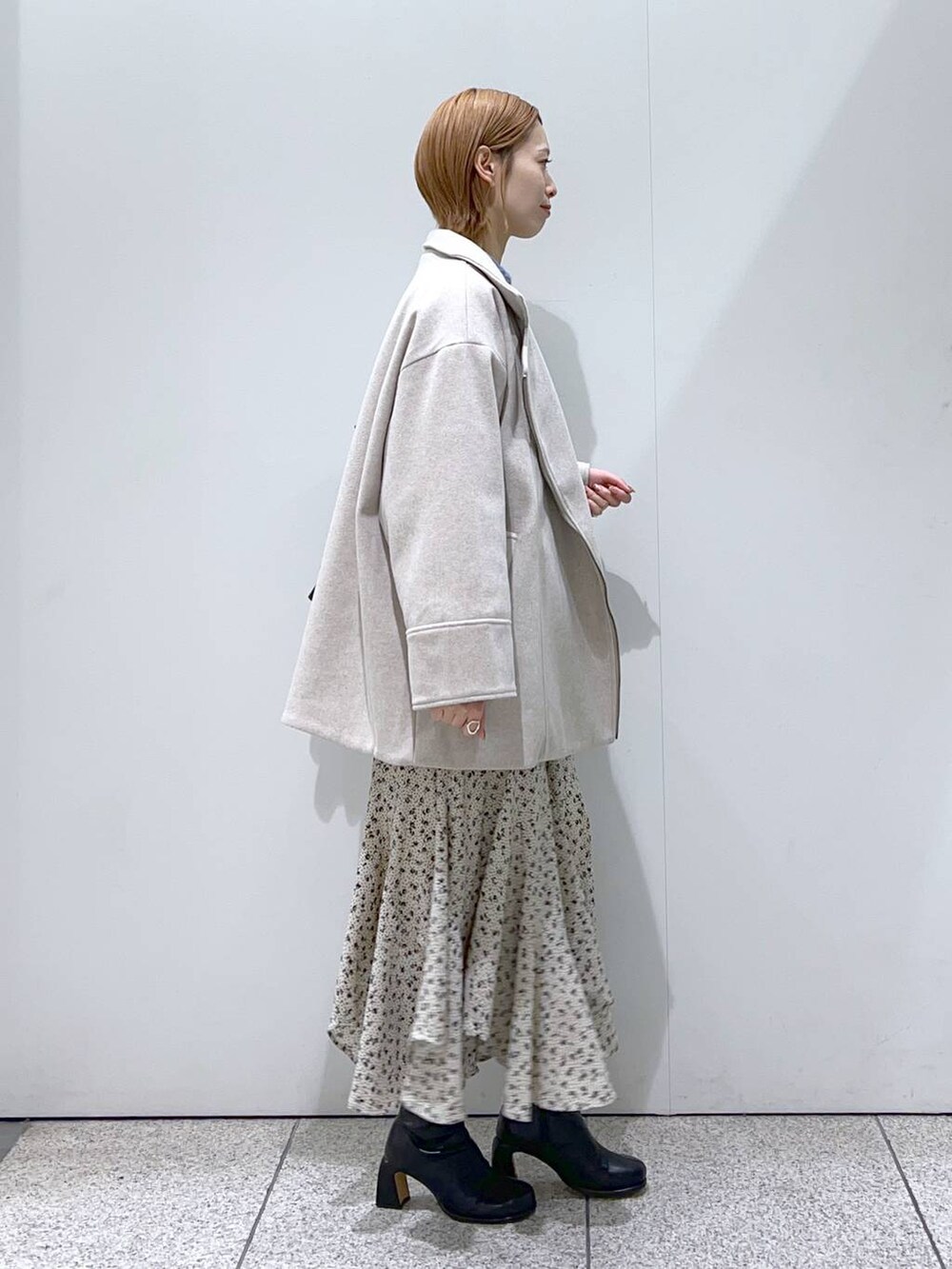 ブラック系のブーツ、ブルー系のニット/セーター、ホワイト系のスカートを着用したレディースの冬コーディネートの3枚目の写真