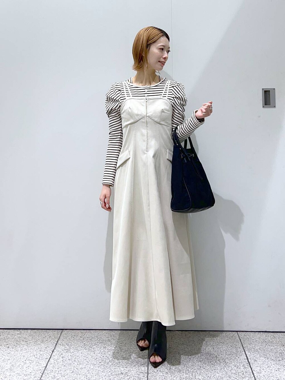 ホワイト系のワンピース、ブラック系のトートバッグ、ホワイト系のTシャツ/カットソーを着用したレディースの冬コーディネートの4枚目の写真