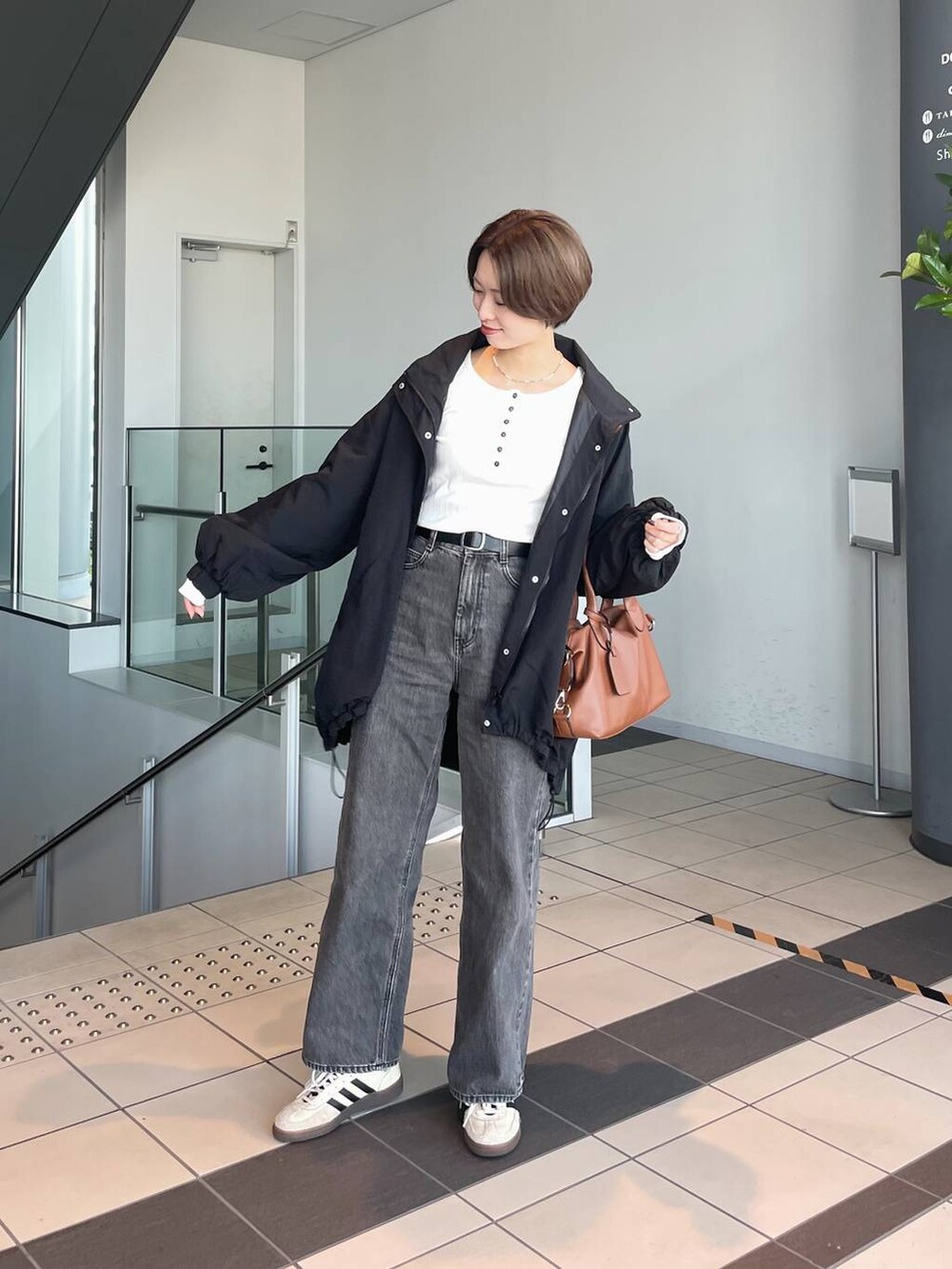 ブラウン系のボストンバッグ、ホワイト系のTシャツ/カットソー、ブラック系のブルゾンを着用したレディースの秋コーディネートの6枚目の写真