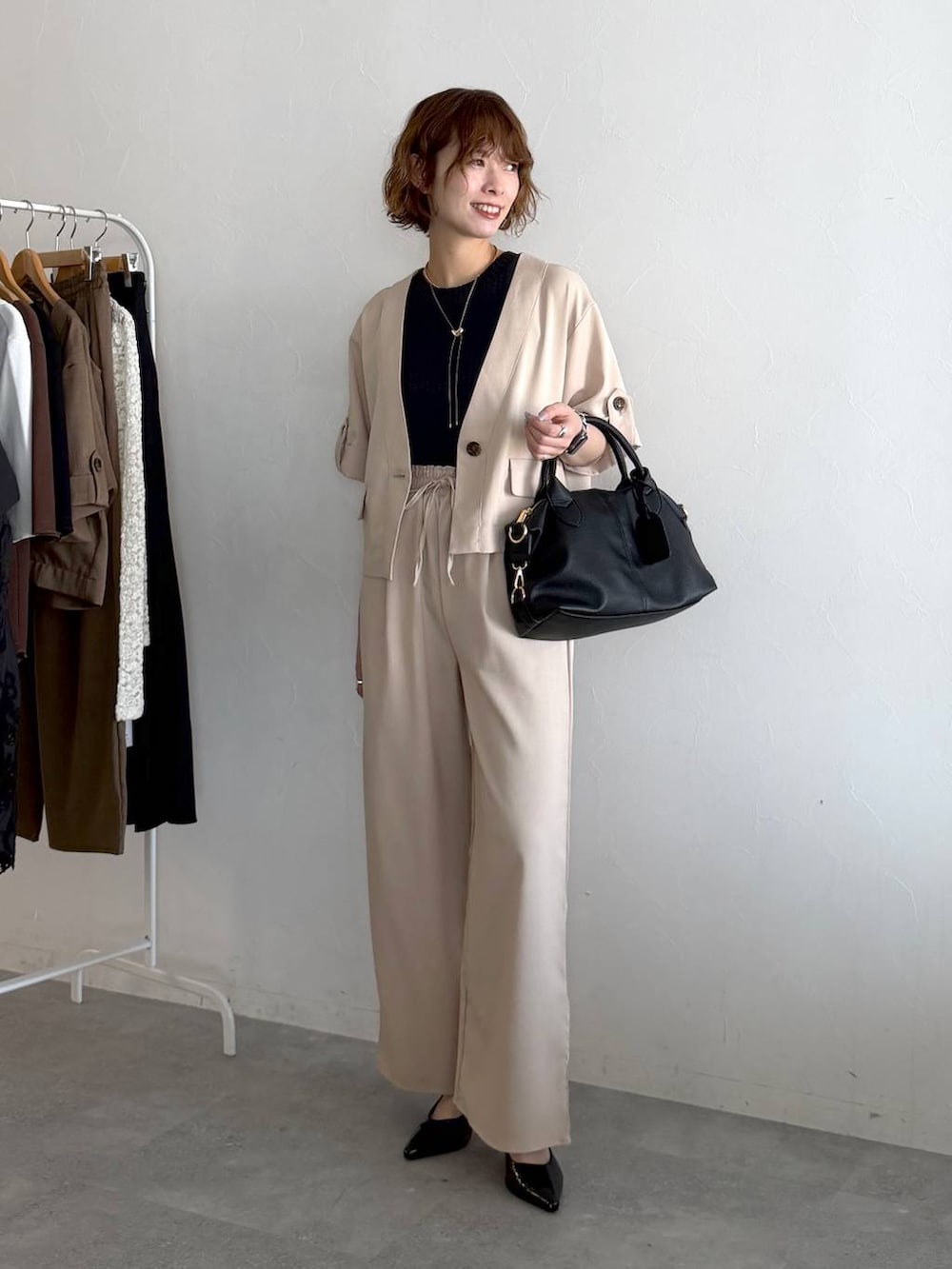 ブラック系のボストンバッグ、ブラック系のサンダル、ホワイト系のセットアップを着用したレディースの春コーディネートの5枚目の写真