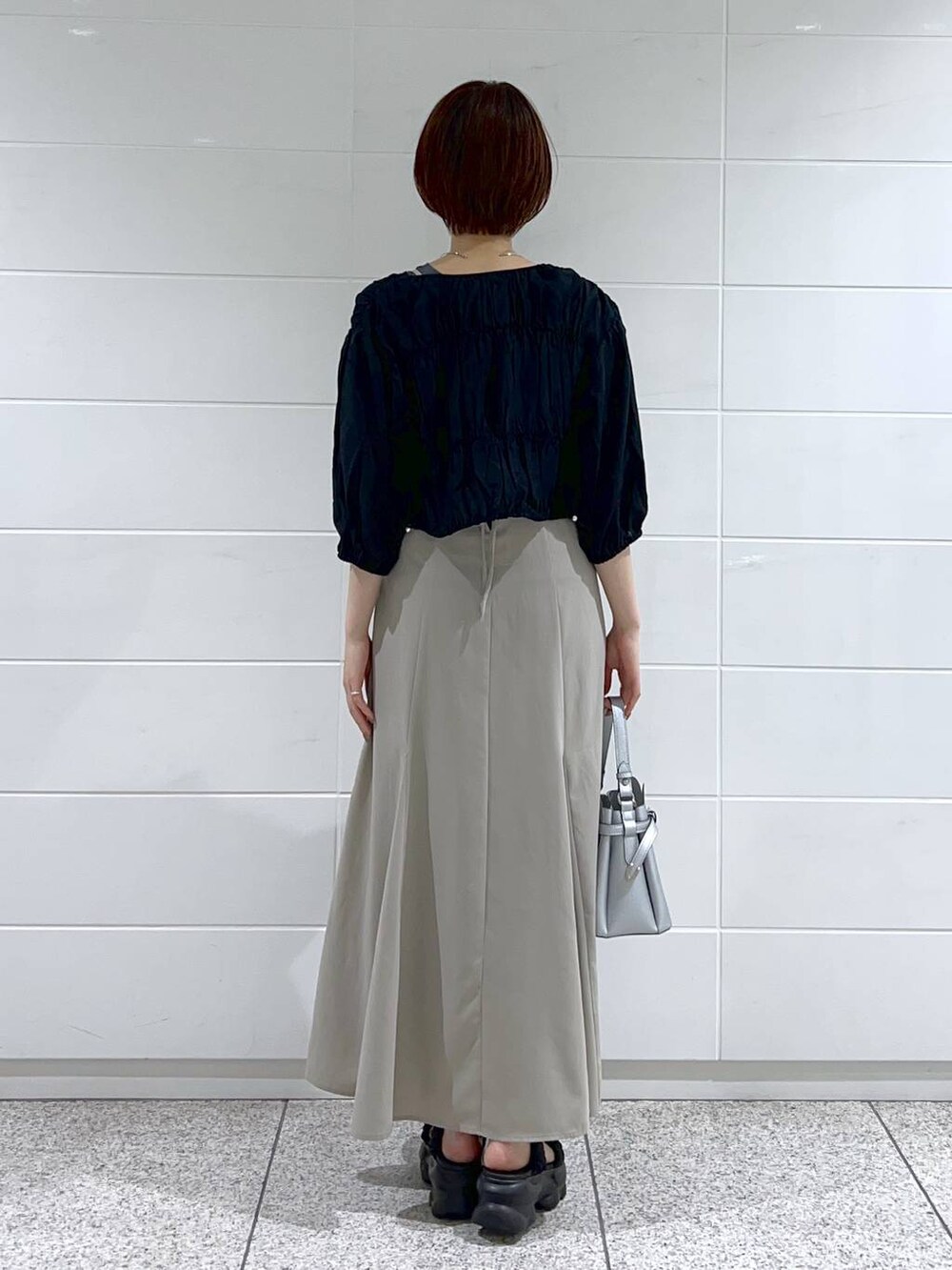 ブラック系のブルゾン、シルバー系のショルダーバッグ、ベージュ系のワンピースを着用したレディースの夏コーディネートの3枚目の写真