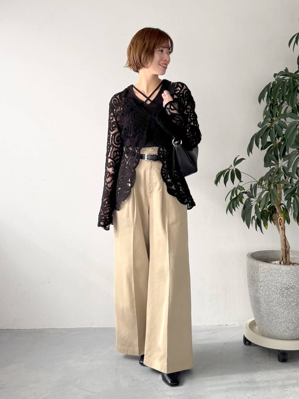 ブラック系のカーディガン/ボレロ、ブラック系のショルダーバッグ、ベージュ系のチノパンツを着用したレディースの春コーディネートの4枚目の写真