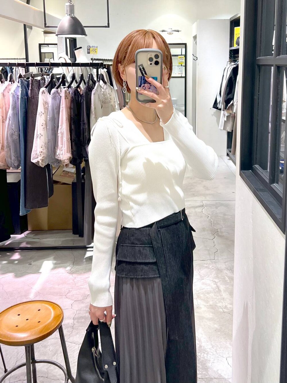 ブラック系のスカート、ホワイト系のカーディガン/ボレロ、ブラック系のサンダルを着用したレディースの春コーディネートの6枚目の写真