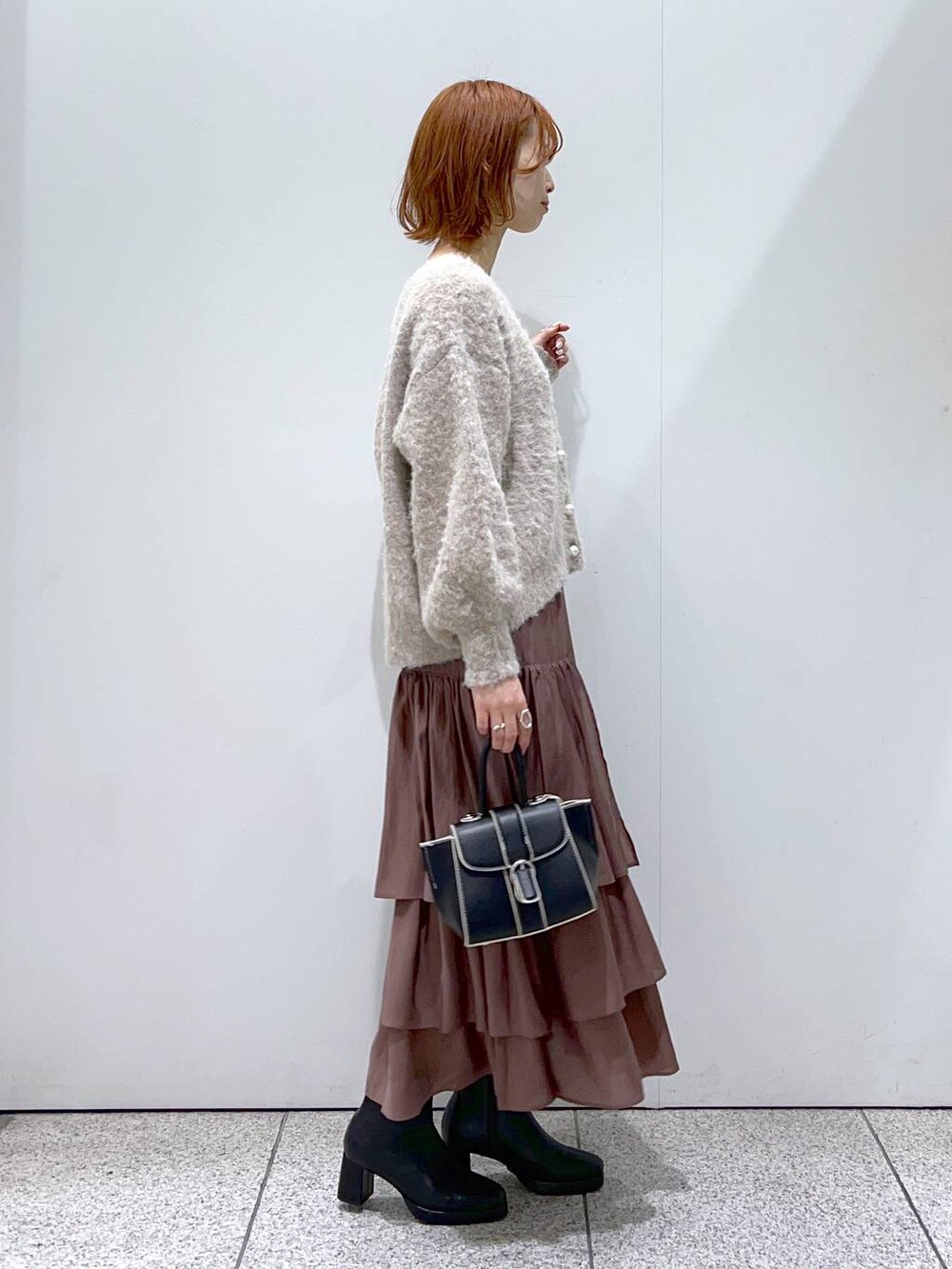 ブラック系のハンドバッグ、ブラック系のブーツ、ブラウン系のカーディガン/ボレロを着用したレディースの秋コーディネートの2枚目の写真