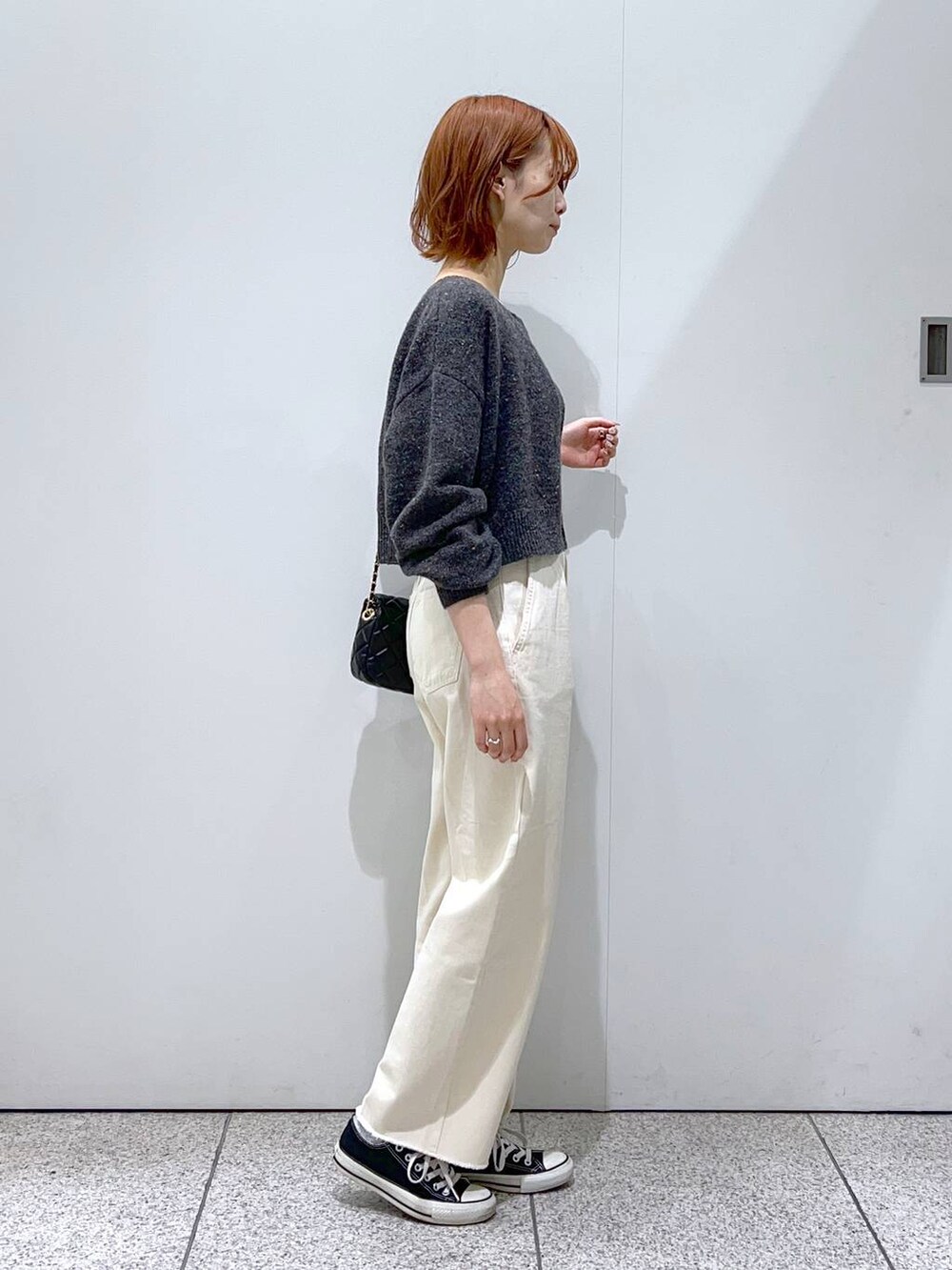 ブラック系のショルダーバッグ、ホワイト系のデニムパンツ、ホワイト系のニット/セーターを着用したレディースの秋コーディネートの2枚目の写真