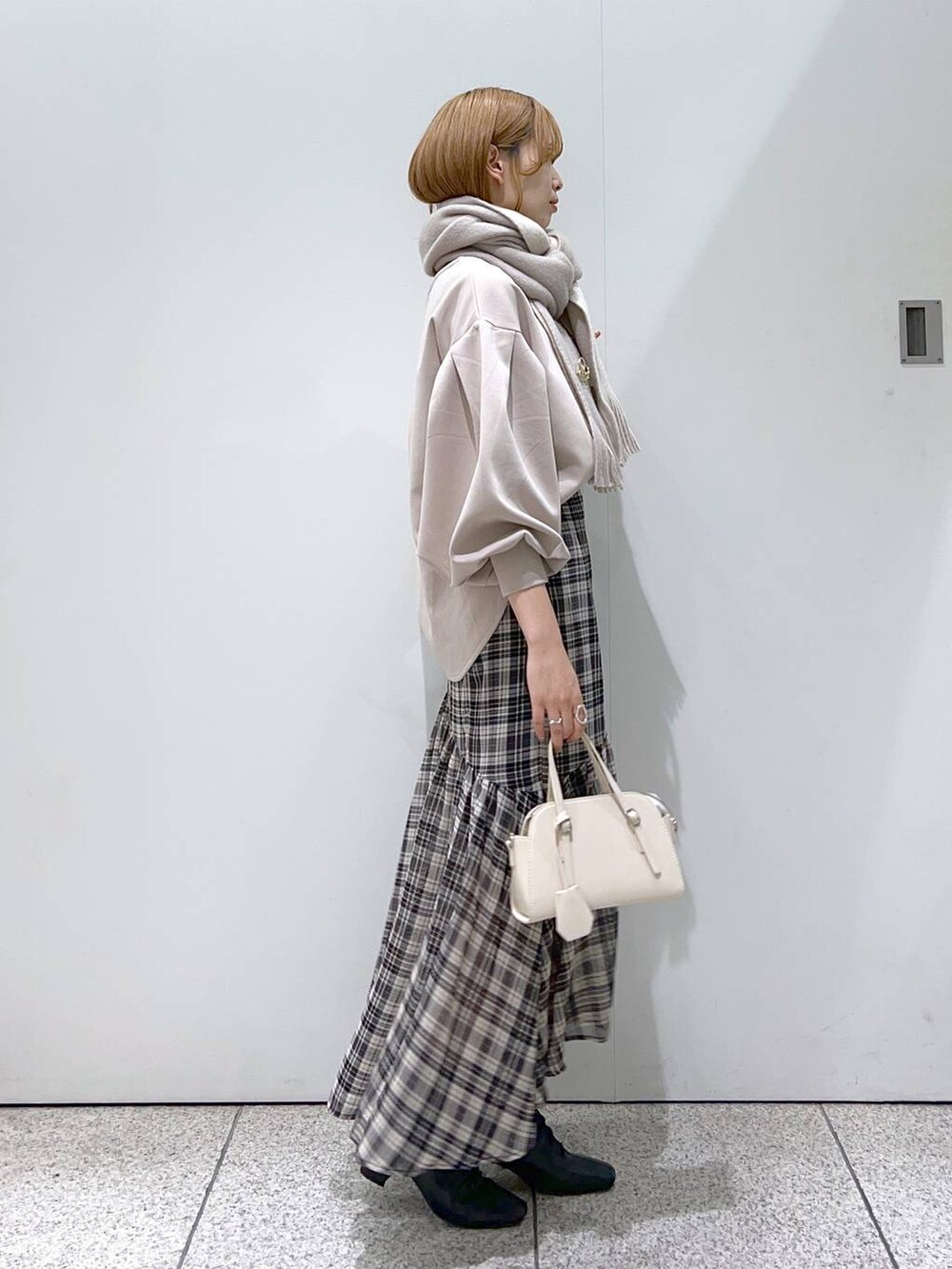 ホワイト系のボストンバッグ、ベージュ系のTシャツ/カットソー、ブラック系のブーツを着用したレディースの秋コーディネートの2枚目の写真