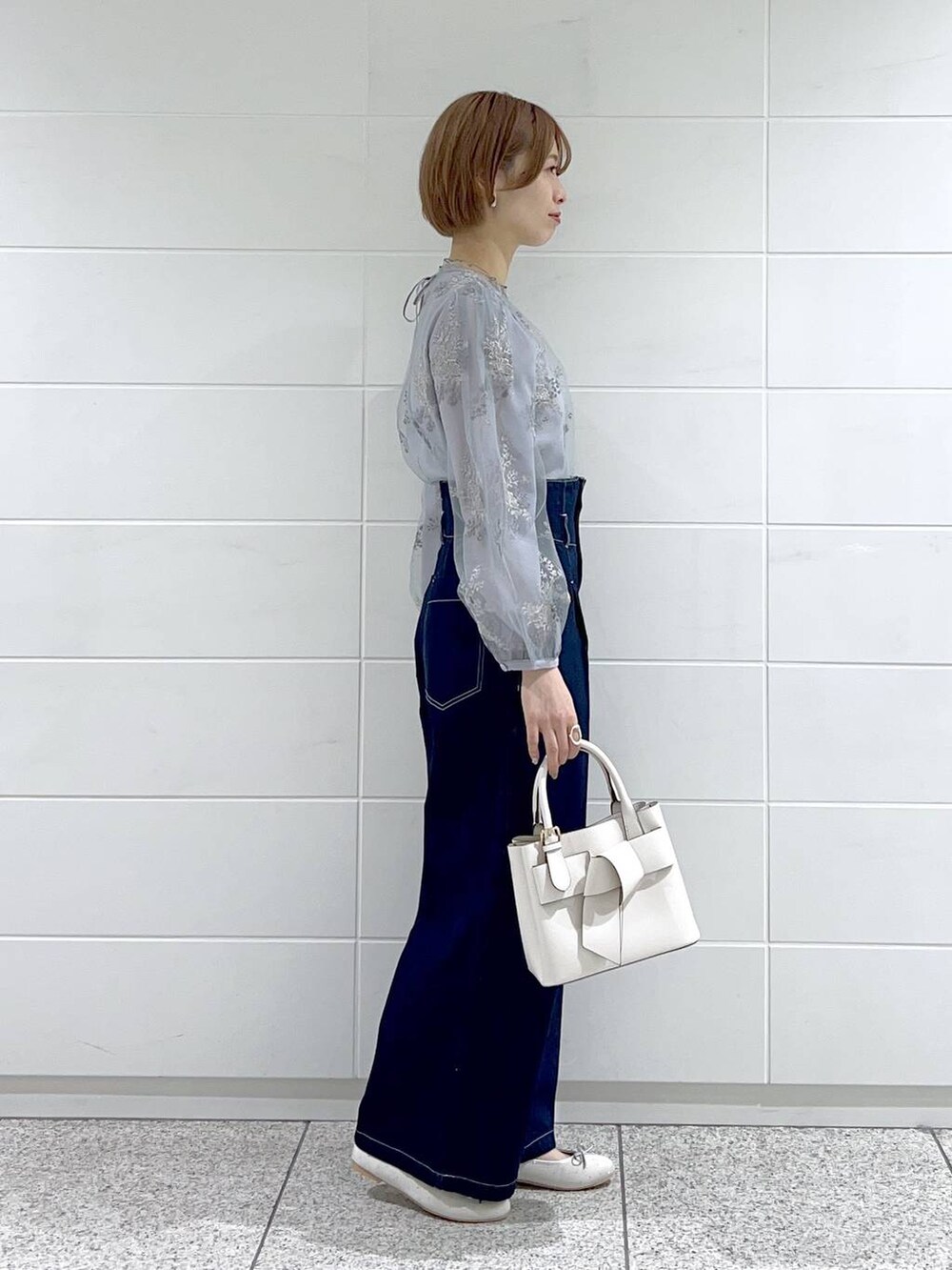 ホワイト系のショルダーバッグ、シルバー系のバレエシューズ、ブルー系のデニムパンツを着用したレディースの春コーディネートの2枚目の写真