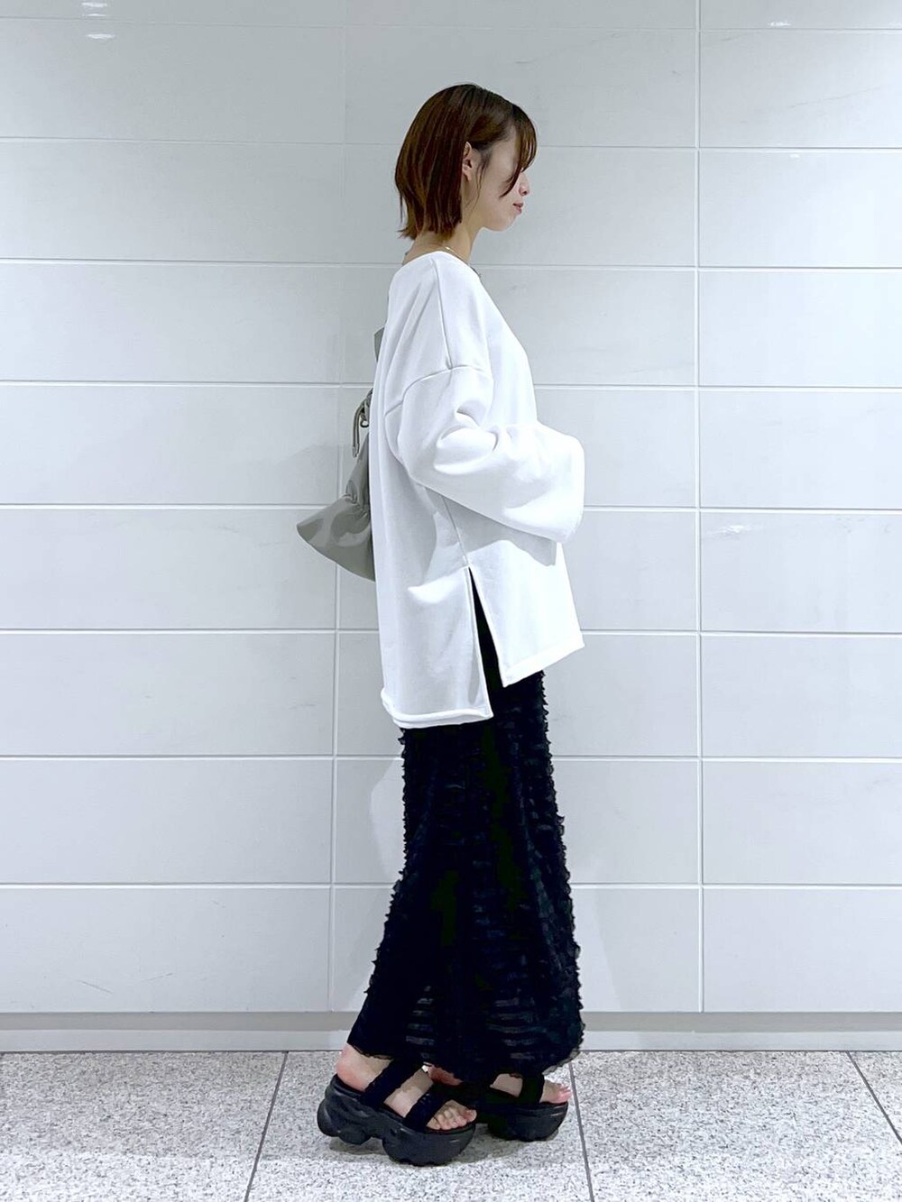 グリーン系のショルダーバッグ、ホワイト系のスウェット、ブラック系のサンダルを着用したレディースの春コーディネートの3枚目の写真