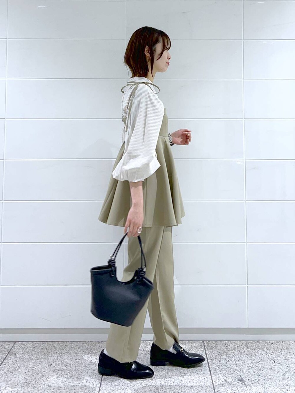 ブラック系のローファー、ブラック系のハンドバッグ、ベージュ系のシャツ/ブラウスを着用したレディースの春コーディネートの2枚目の写真