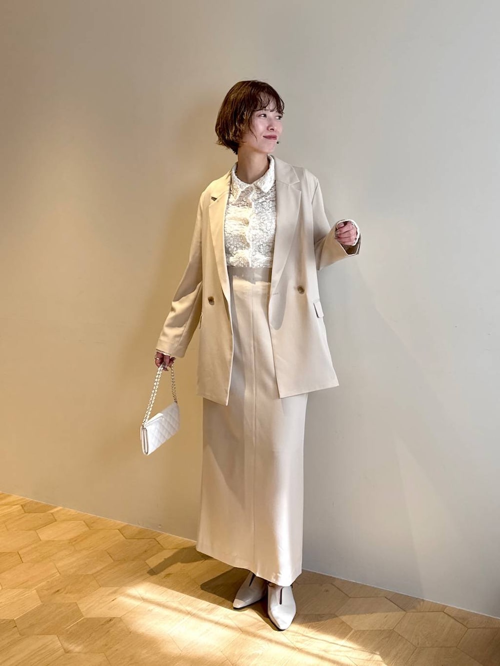 ホワイト系のサンダル、ベージュ系のテーラードジャケット、ベージュ系のスカートを着用したレディースの冬コーディネートの6枚目の写真
