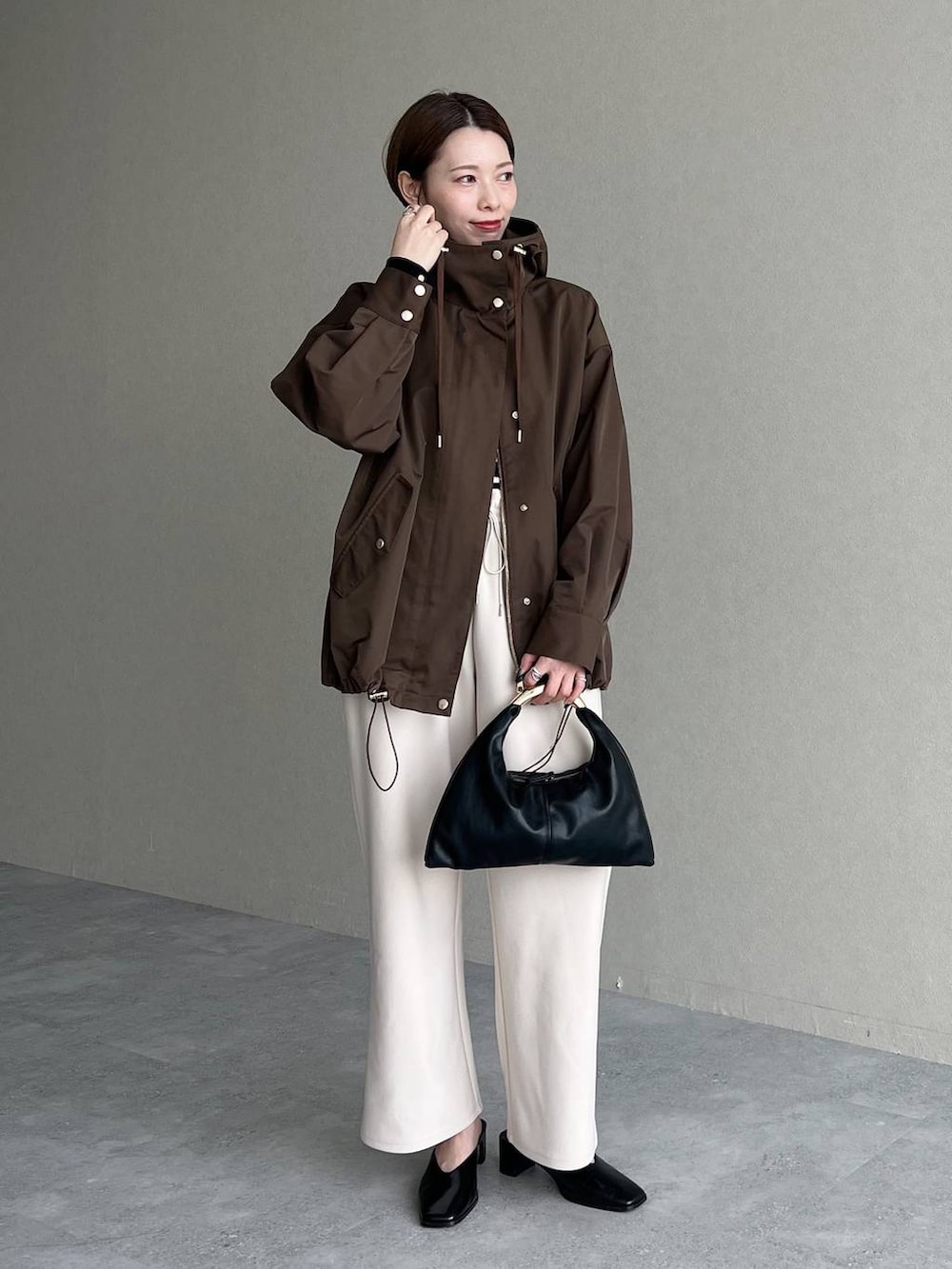 ブラック系のハンドバッグ、ブラウン系のマウンテンパーカー、ブラック系のスリッポンを着用したレディースの秋コーディネートの2枚目の写真