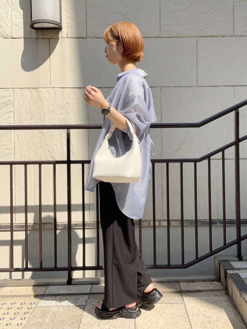 ブラック系のサンダル、ホワイト系のショルダーバッグ、ブラック系のスラックスを着用したレディースの夏コーディネートの2枚目の写真