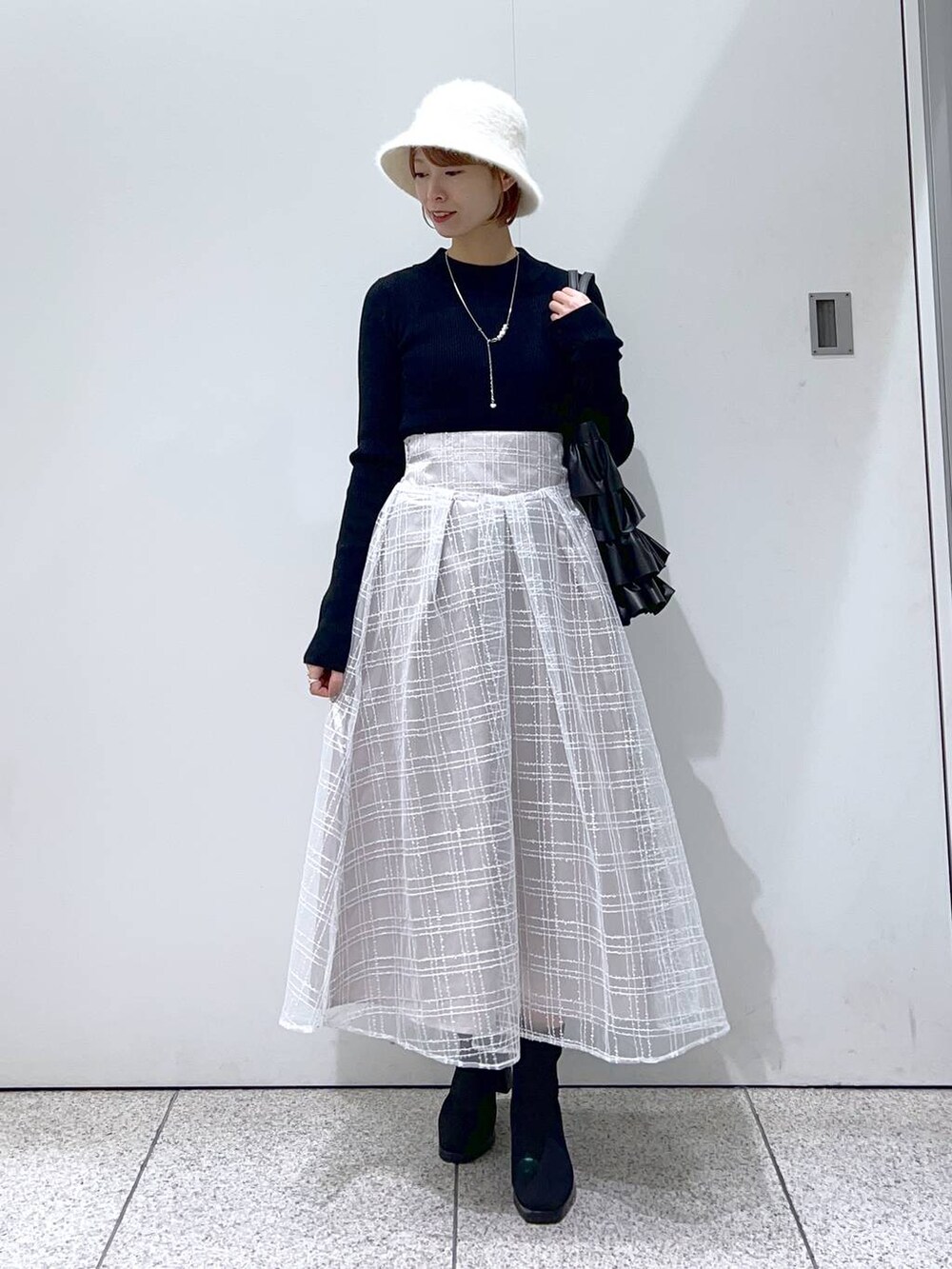 ブラウン系のチェスターコート、ブラック系のブーツ、ブラック系のニット/セーターを着用したレディースの冬コーディネートの4枚目の写真