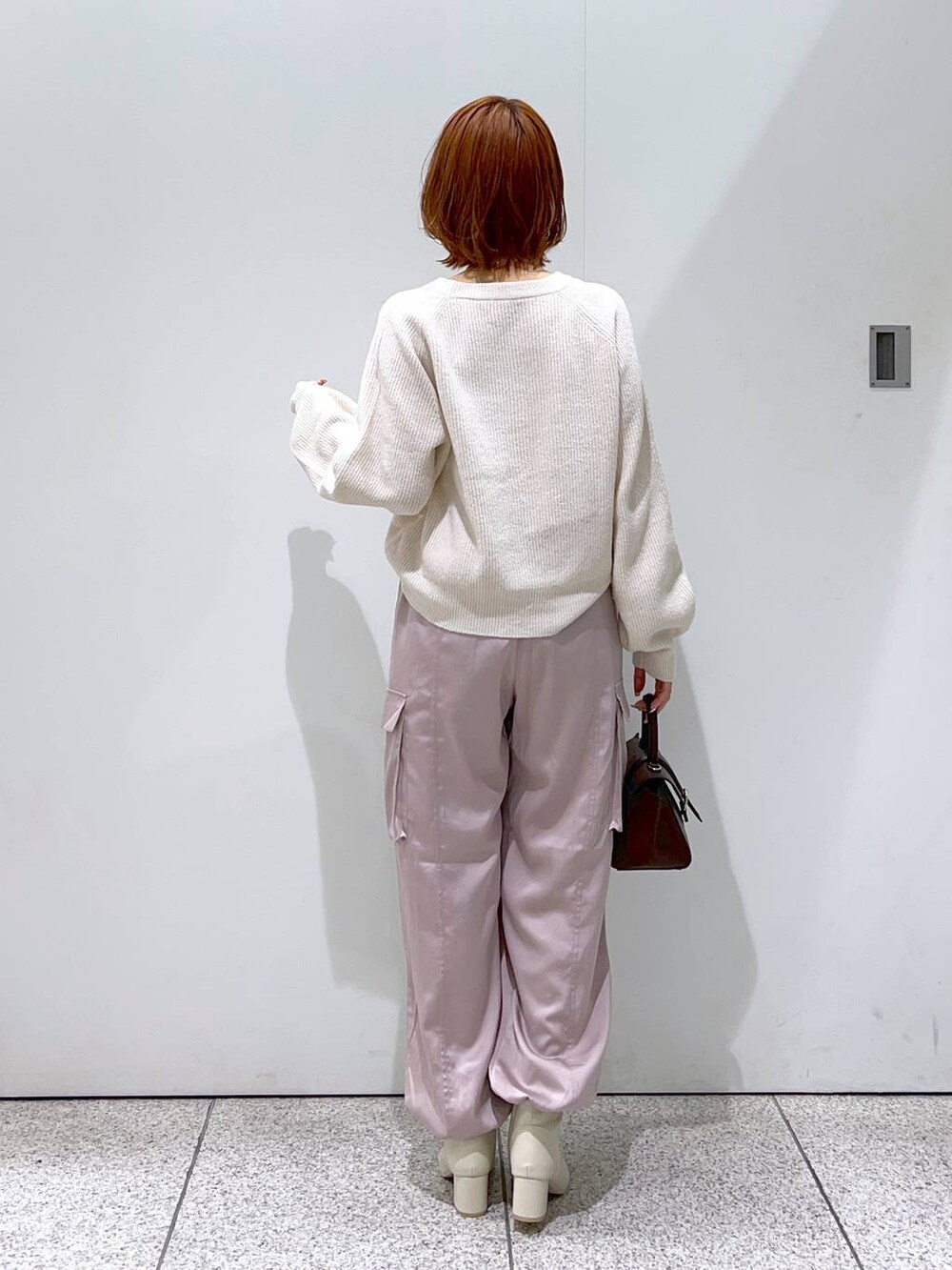 ホワイト系のニット/セーター、ブラウン系のハンドバッグ、ホワイト系のブーツを着用したレディースの秋コーディネートの3枚目の写真