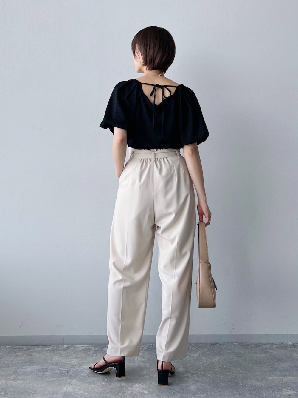 ブラック系のTシャツ/カットソー、ブラウン系のバッグ、ホワイト系のパンツを着用したレディースの夏コーディネートの3枚目の写真