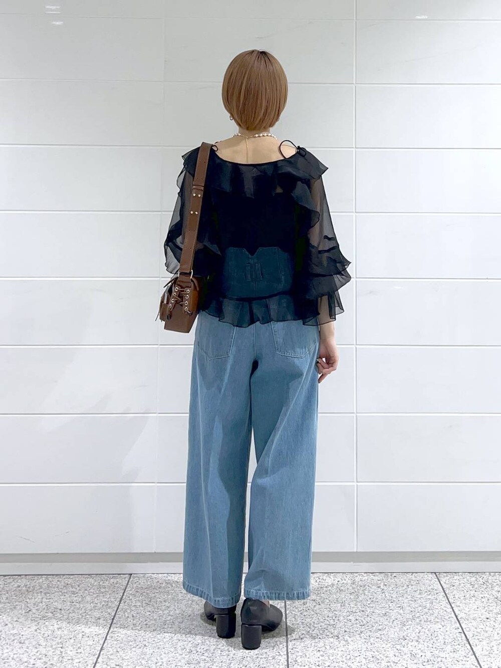 ブラック系のパンプス、ブルー系のデニムパンツ、ブラック系のシャツ/ブラウスを着用したレディースの春コーディネートの3枚目の写真
