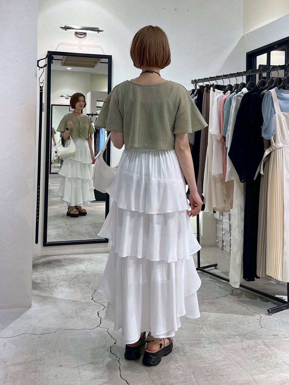 グリーン系のカーディガン/ボレロ、ベージュ系のサンダル、ホワイト系のショルダーバッグを着用したレディースの夏コーディネートの3枚目の写真