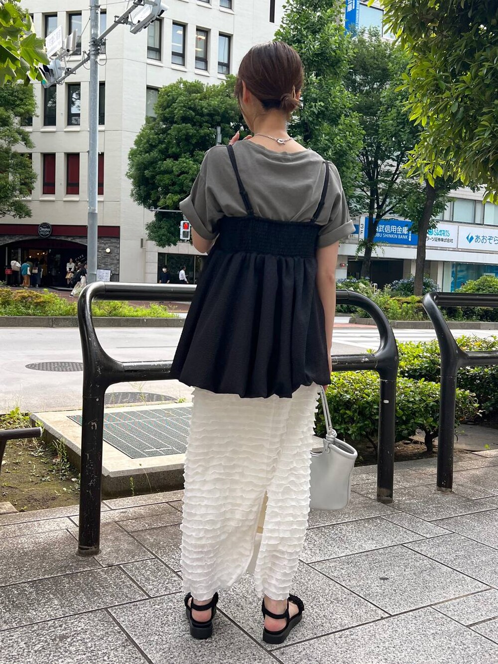 ブラック系のサンダル、シルバー系のハンドバッグ、ホワイト系のスカートを着用したレディースの夏コーディネートの2枚目の写真