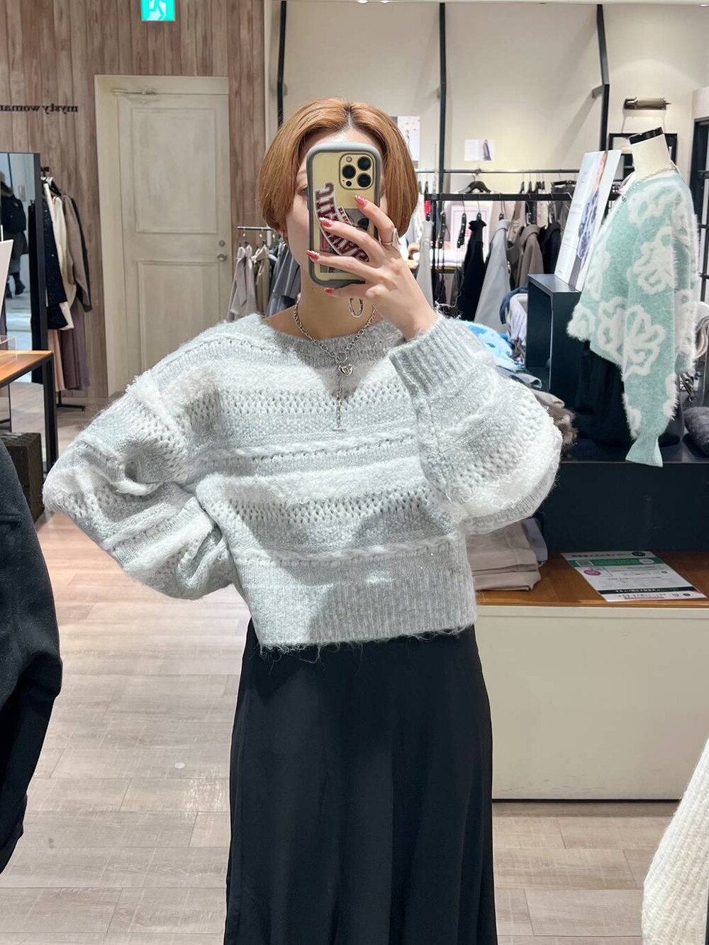 シルバー系のショルダーバッグ、ブラック系のブーツ、ブラック系のスカートを着用したレディースの冬コーディネートの4枚目の写真