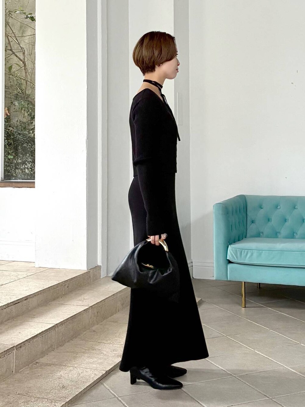 ブラック系のハンドバッグ、ホワイト系のステンカラーコート、ブラック系のブーツを着用したレディースの秋コーディネートの3枚目の写真