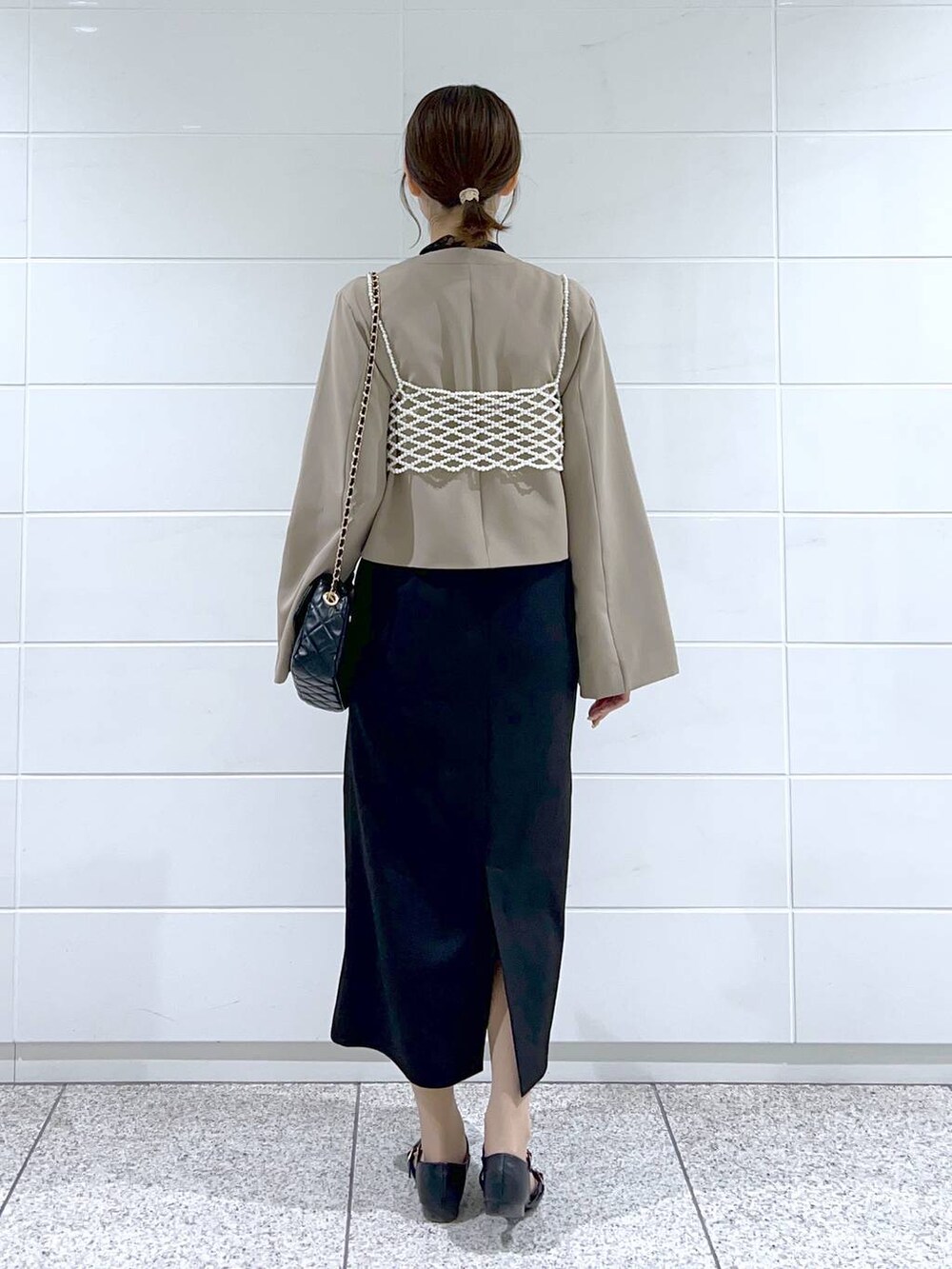 ブラック系のドレス、ブラック系のショルダーバッグ、ブラック系のパンプスを着用したレディースの春コーディネートの3枚目の写真